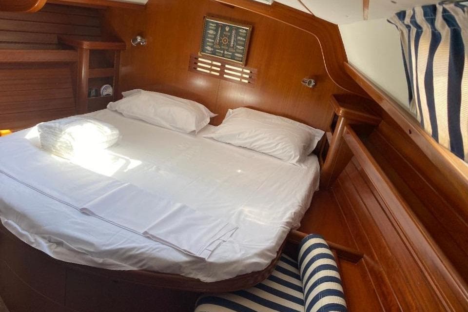 Cozy cabin interior of 2002 Beneteau 50 yacht with wooden finish and striped upholstery.