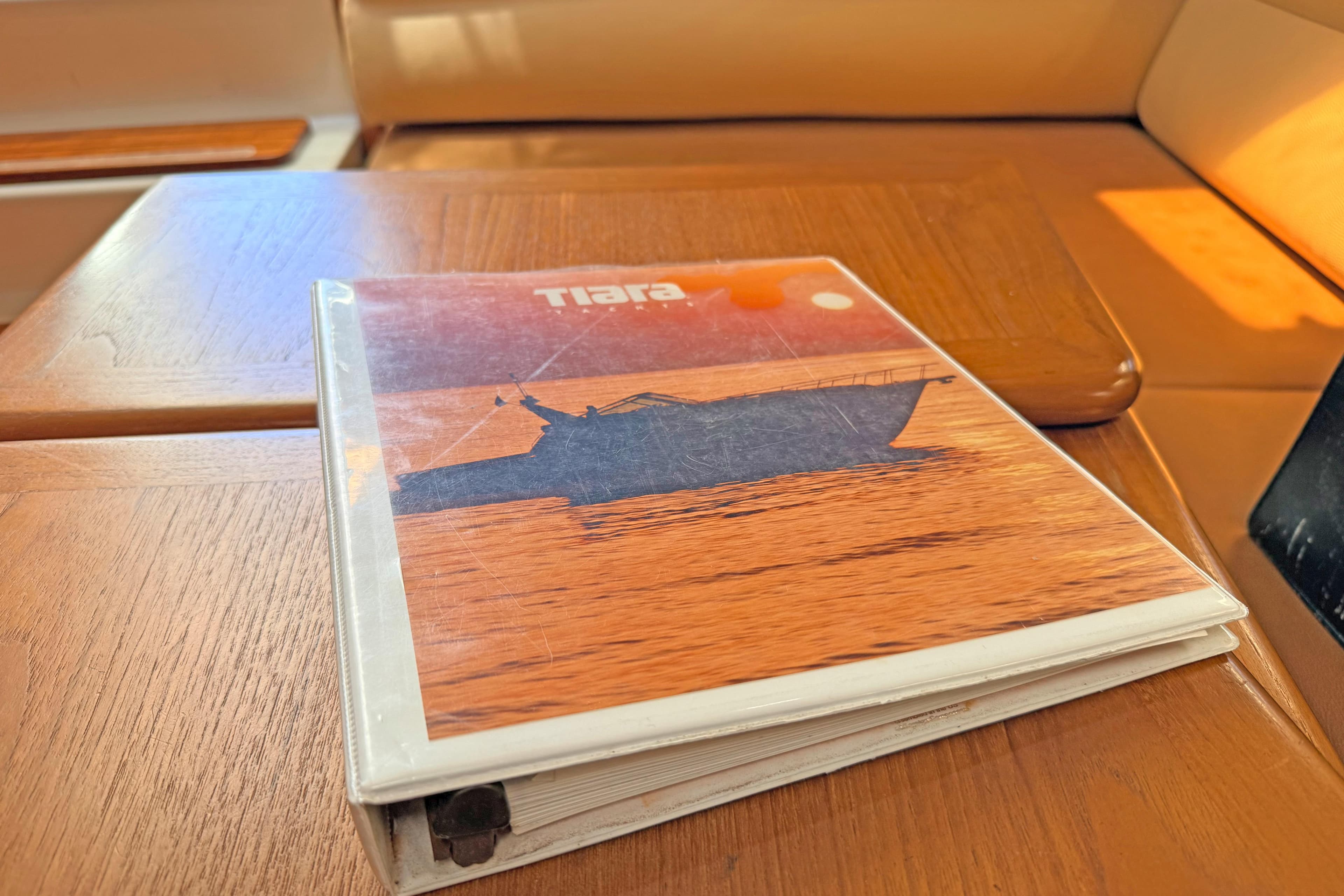 Binder with Tiara 3700 Open Hardtop 1996 brochure on wooden table.