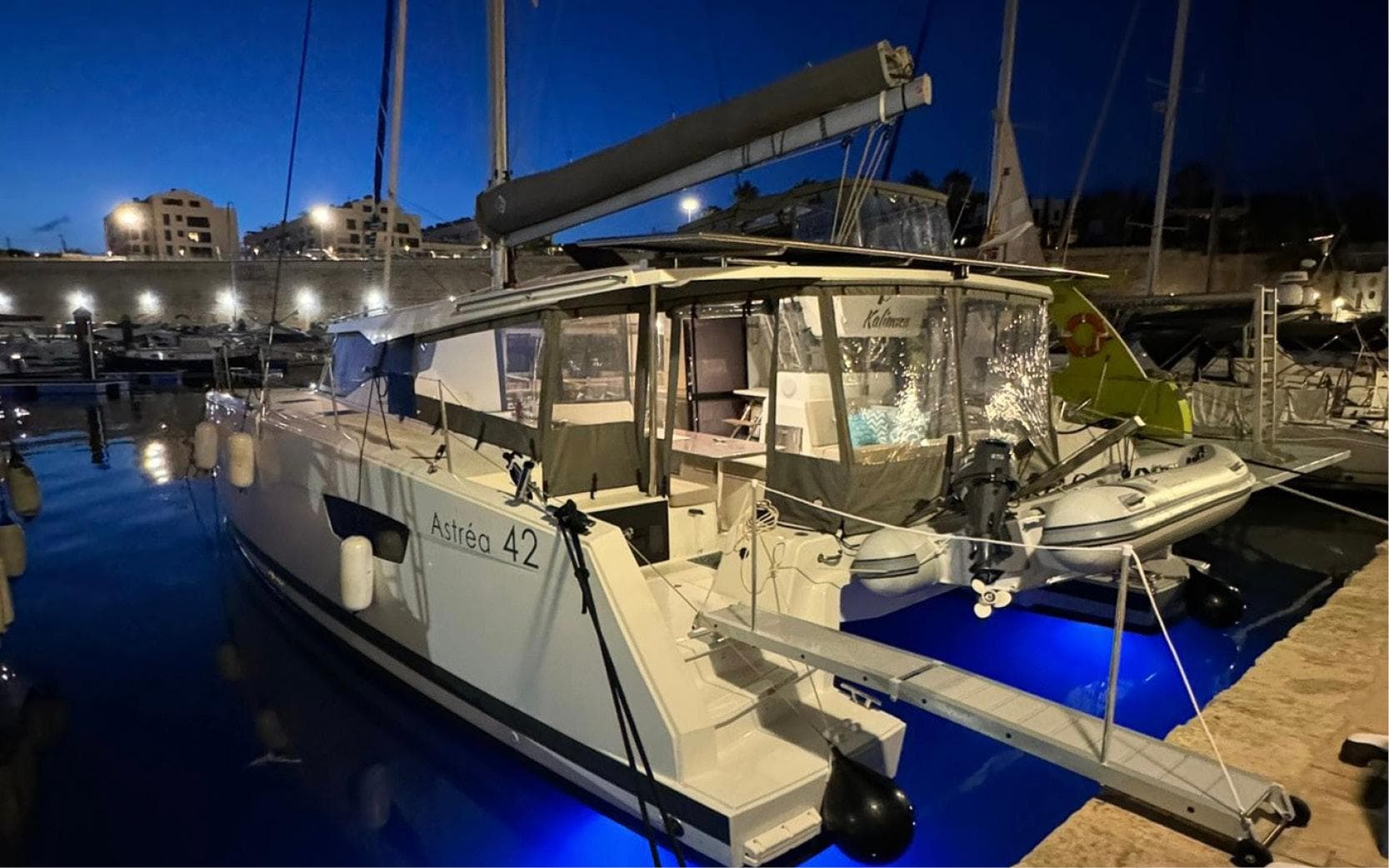 2023 Fountaine Pajot Astrea 42 catamaran docked at night with blue underwater lights.