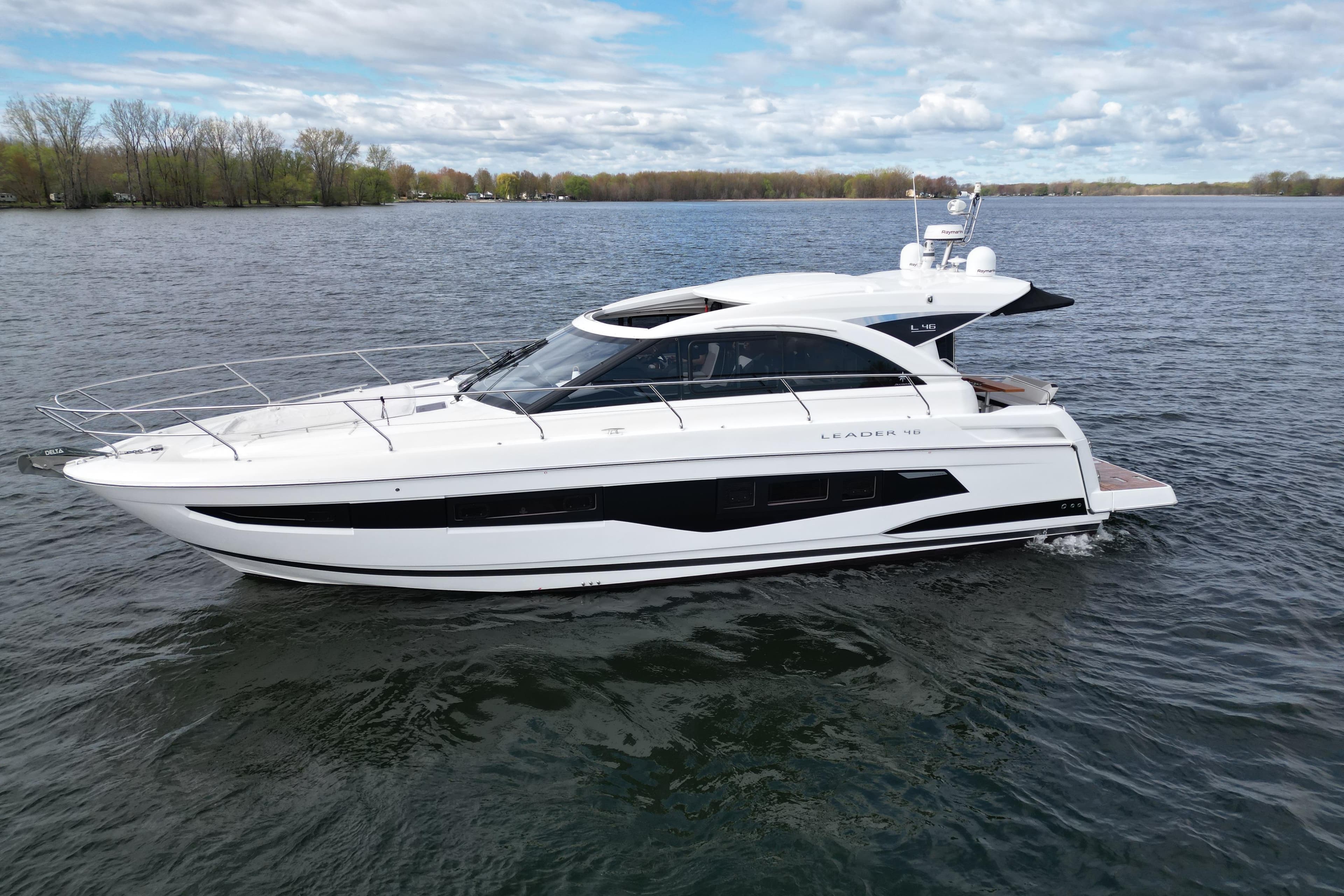 2022 Jeanneau Leader 46 yacht cruising on a serene lake under a partly cloudy sky.