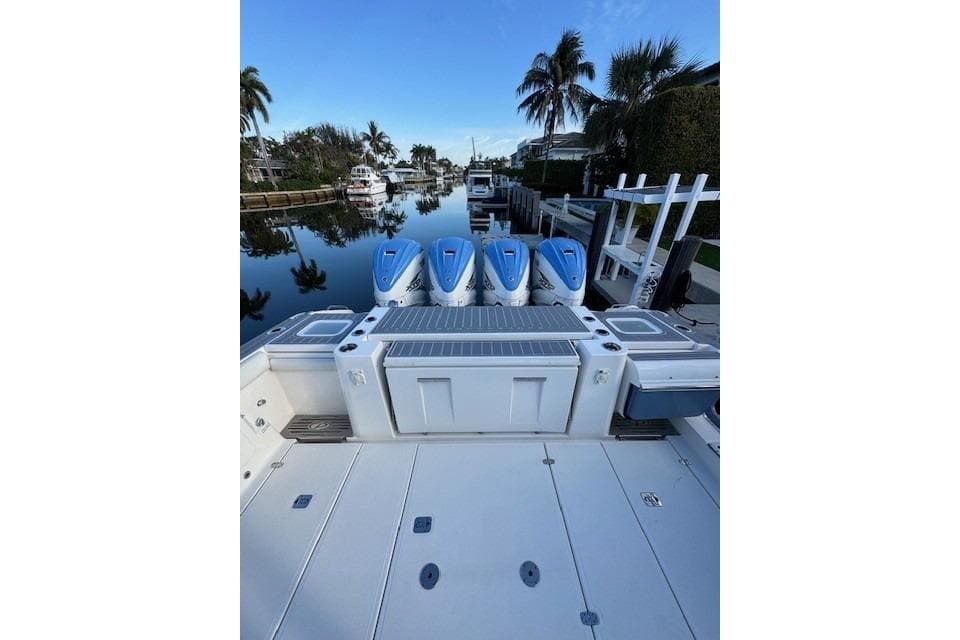2023 Pursuit S 428 Sport boat with four engines docked by a canal.