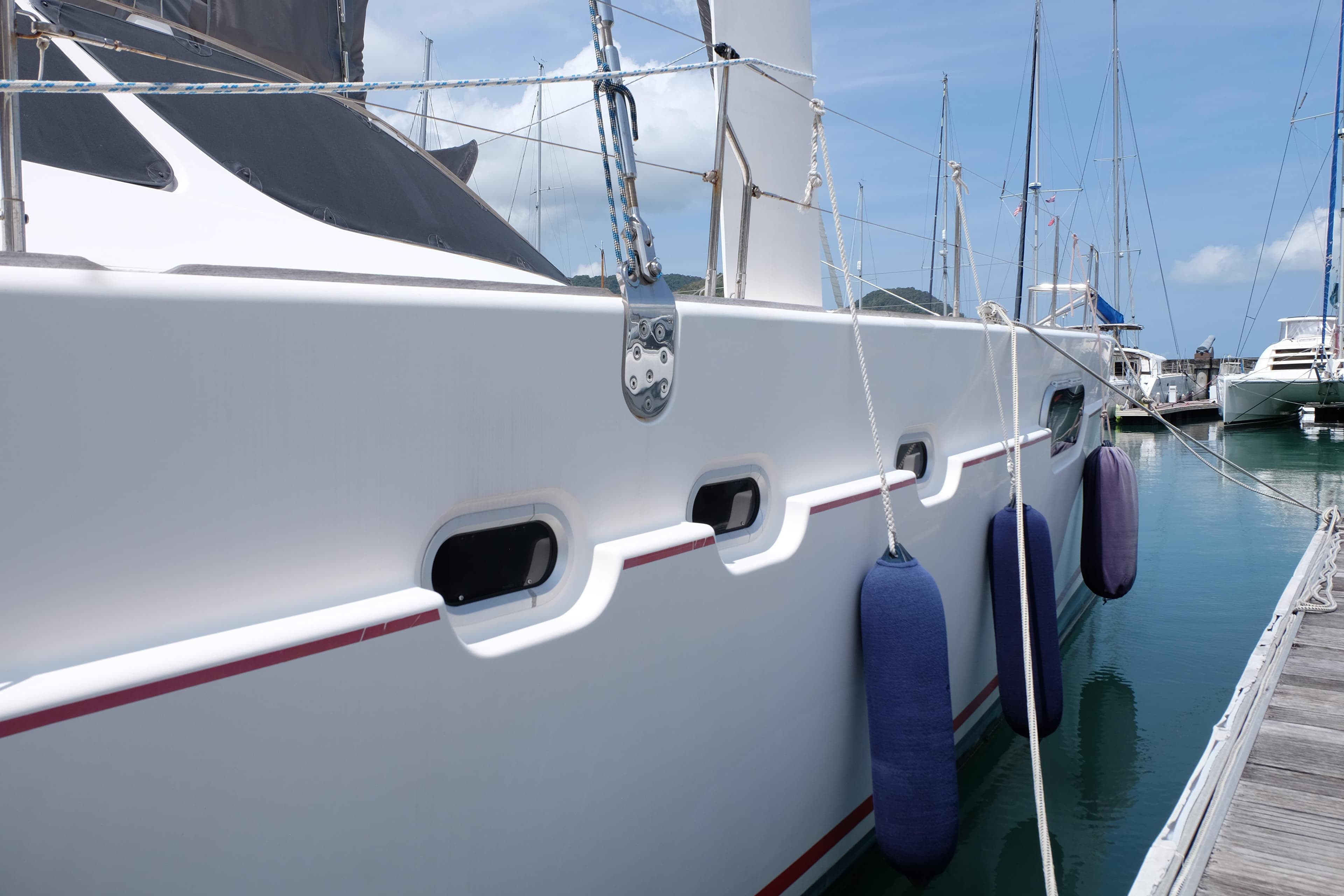 Side view of a 2002 Catana 471 yacht docked with blue fenders.