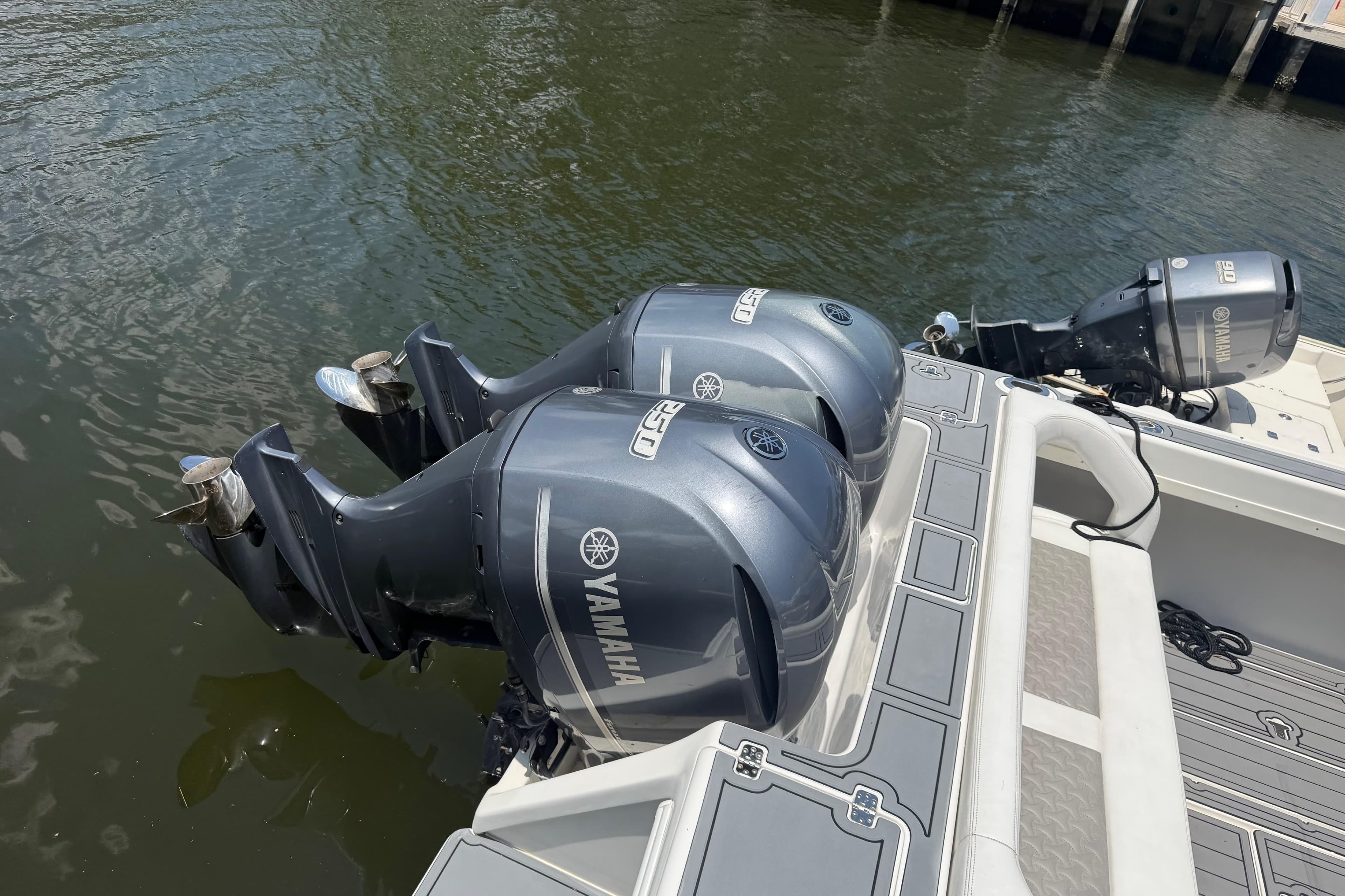 Twin Yamaha outboard engines on a 2003 Intrepid 323 Cuddy boat docked by water.