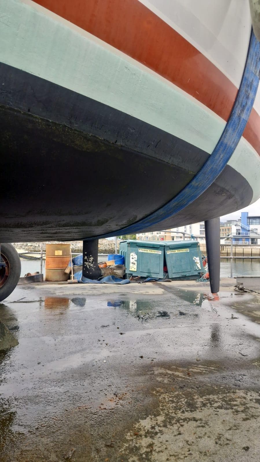 Bottom view of a 1991 Etap 28i sailboat on a wet dockyard surface.