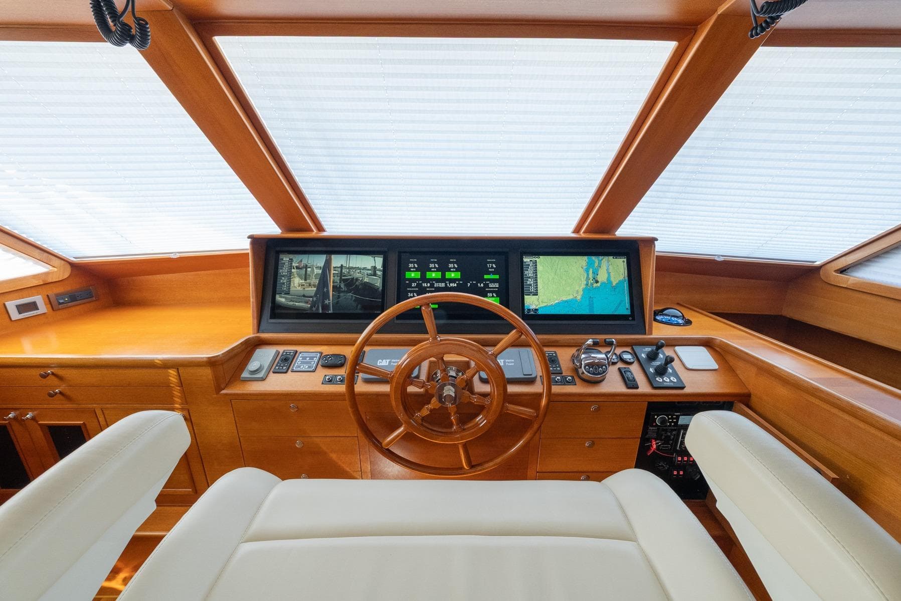 Helm of 2016 Grand Banks 72 Aleutian RP yacht with navigation screens and wooden wheel.
