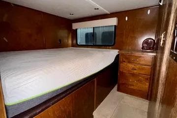 2013 Bravada Bella Luna interior with bed, wooden cabinets, and window.
