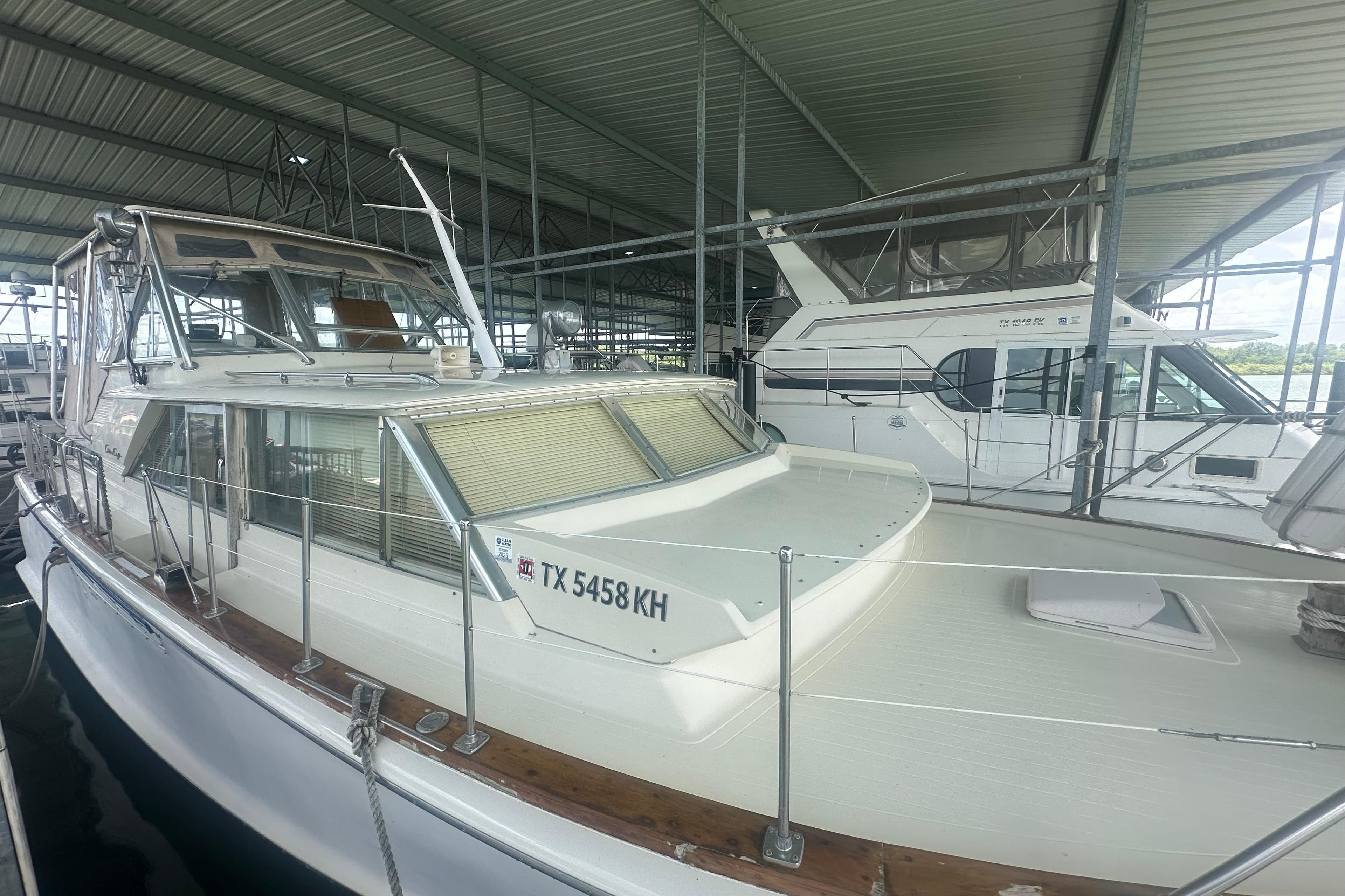 1971 Chris-Craft Commander 42 boat docked in a covered marina, side view.