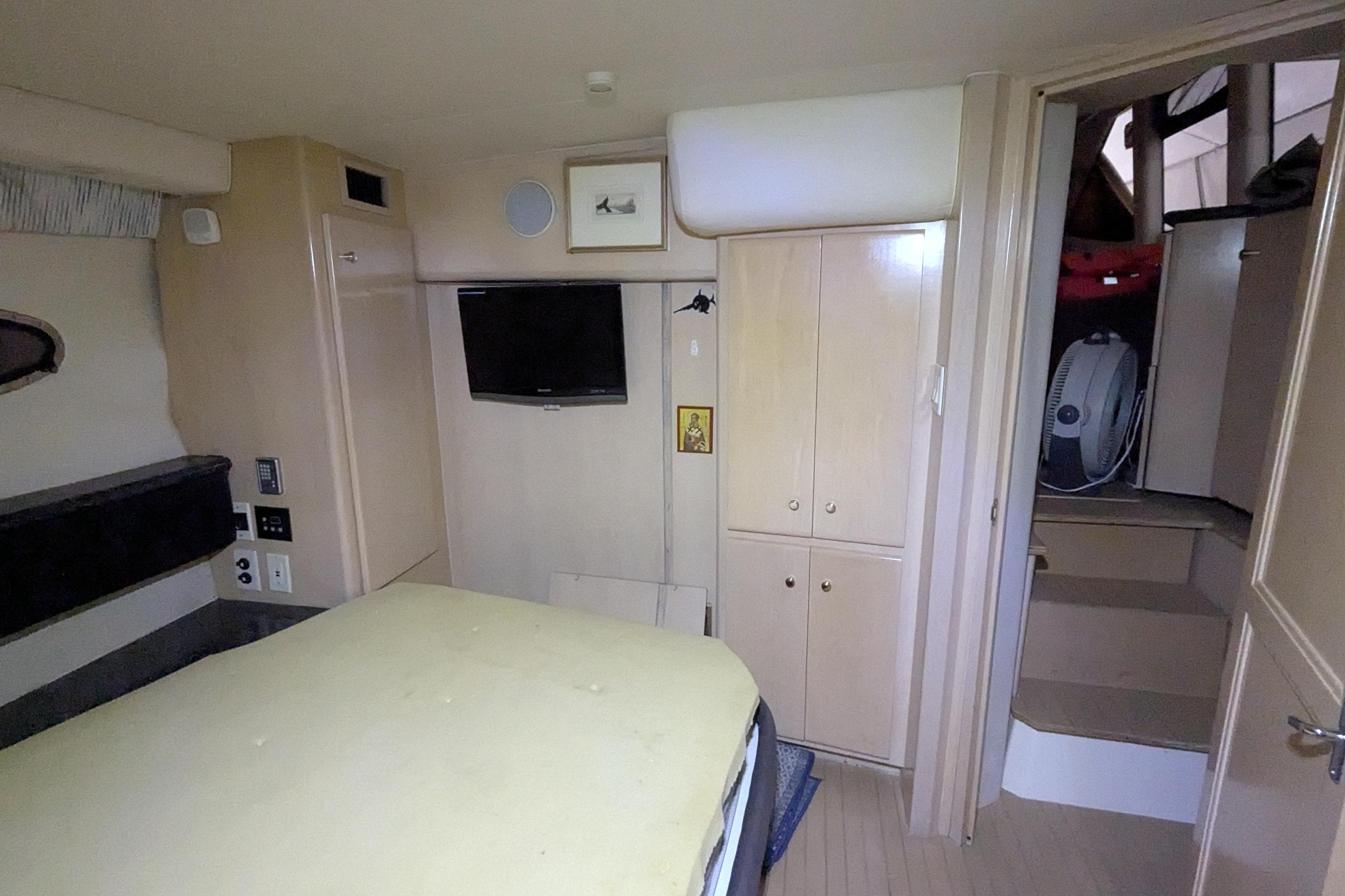 Interior of 2000 Carver 404 Cockpit Motor Yacht with bed, TV, and storage cabinets.