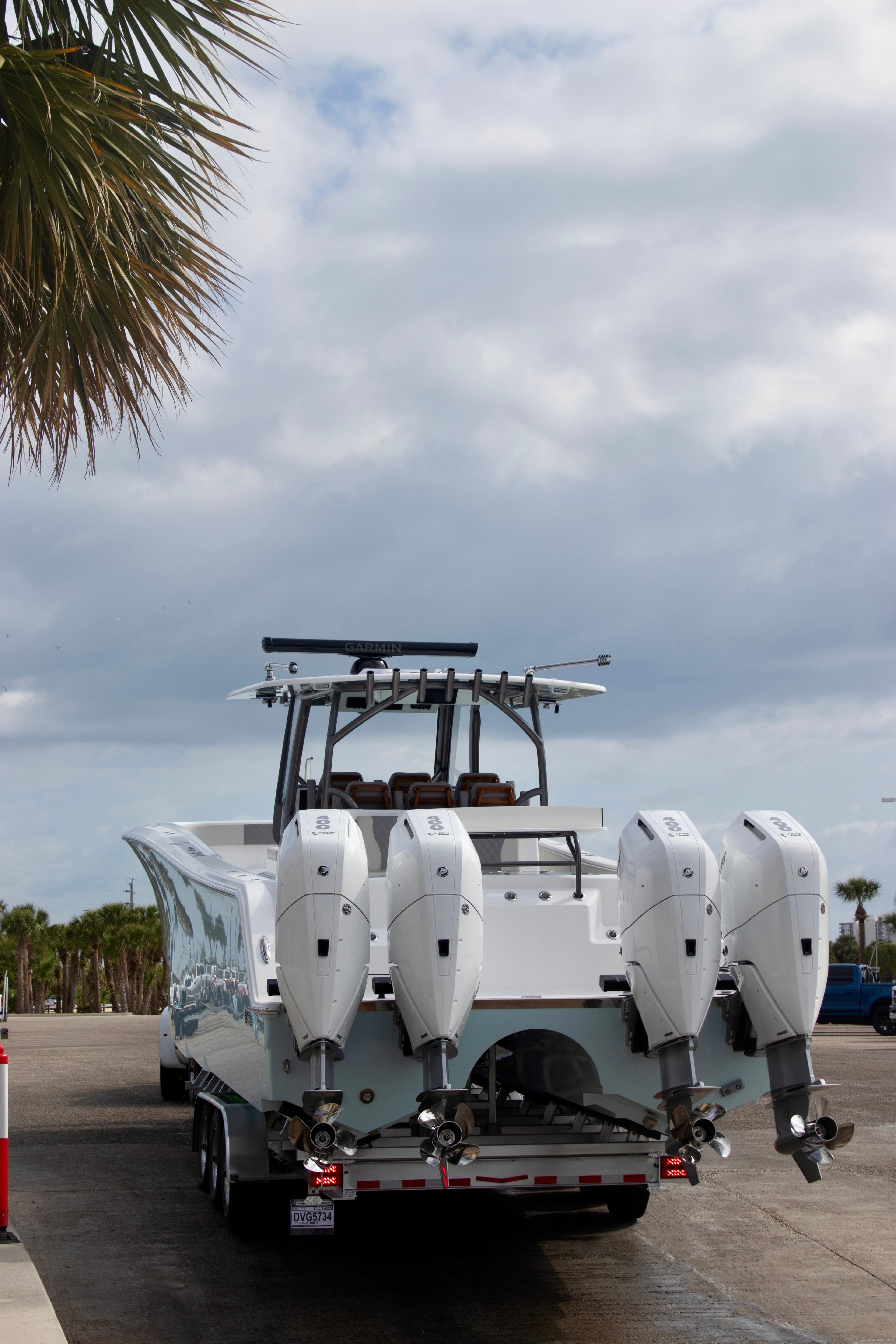 Front Runner 43 Catamaran 2026 with four outboard engines on a trailer, parked near palm trees.