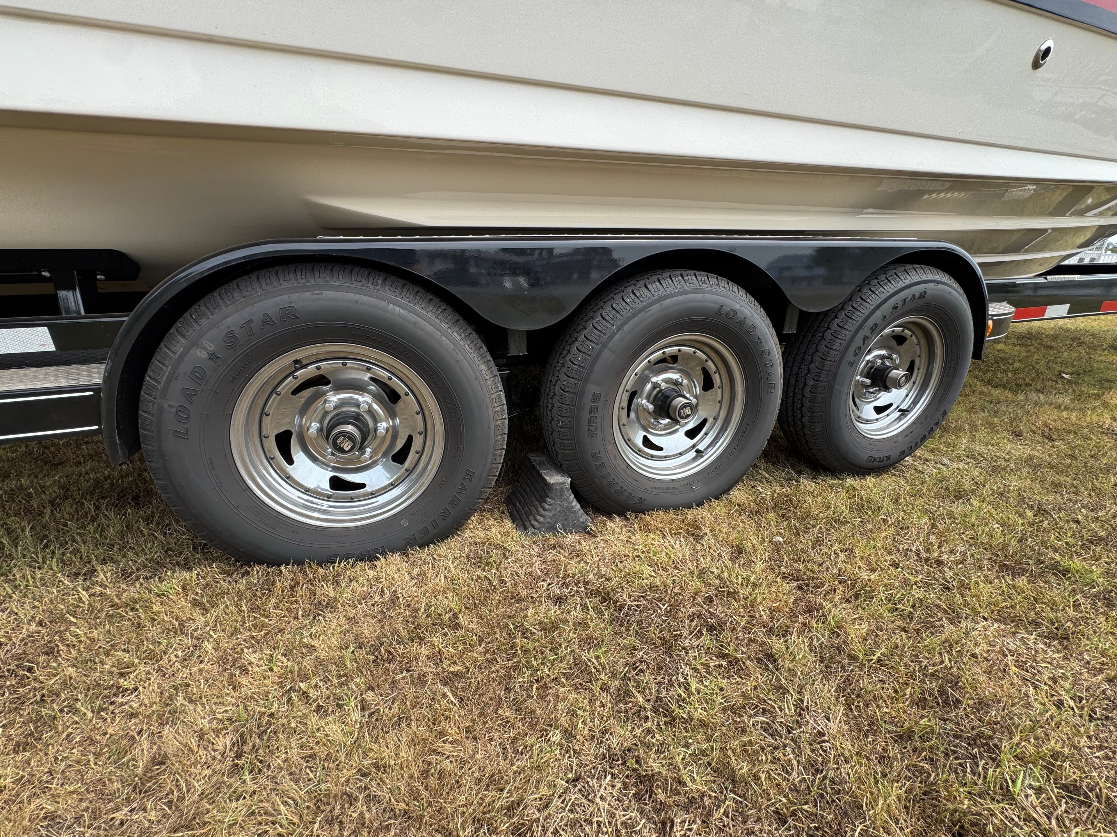 Trailer with triple axles for 2022 Sea Ray SLX 310 boat on grass.
