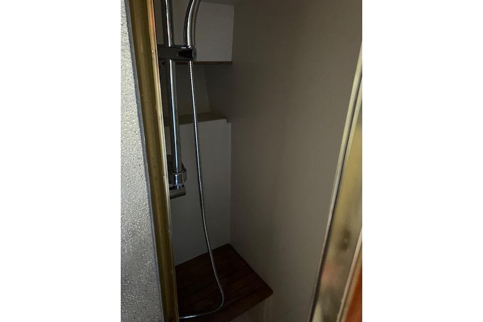 Shower area inside 1985 Egg Harbor 33 Convertible boat, featuring a handheld showerhead.