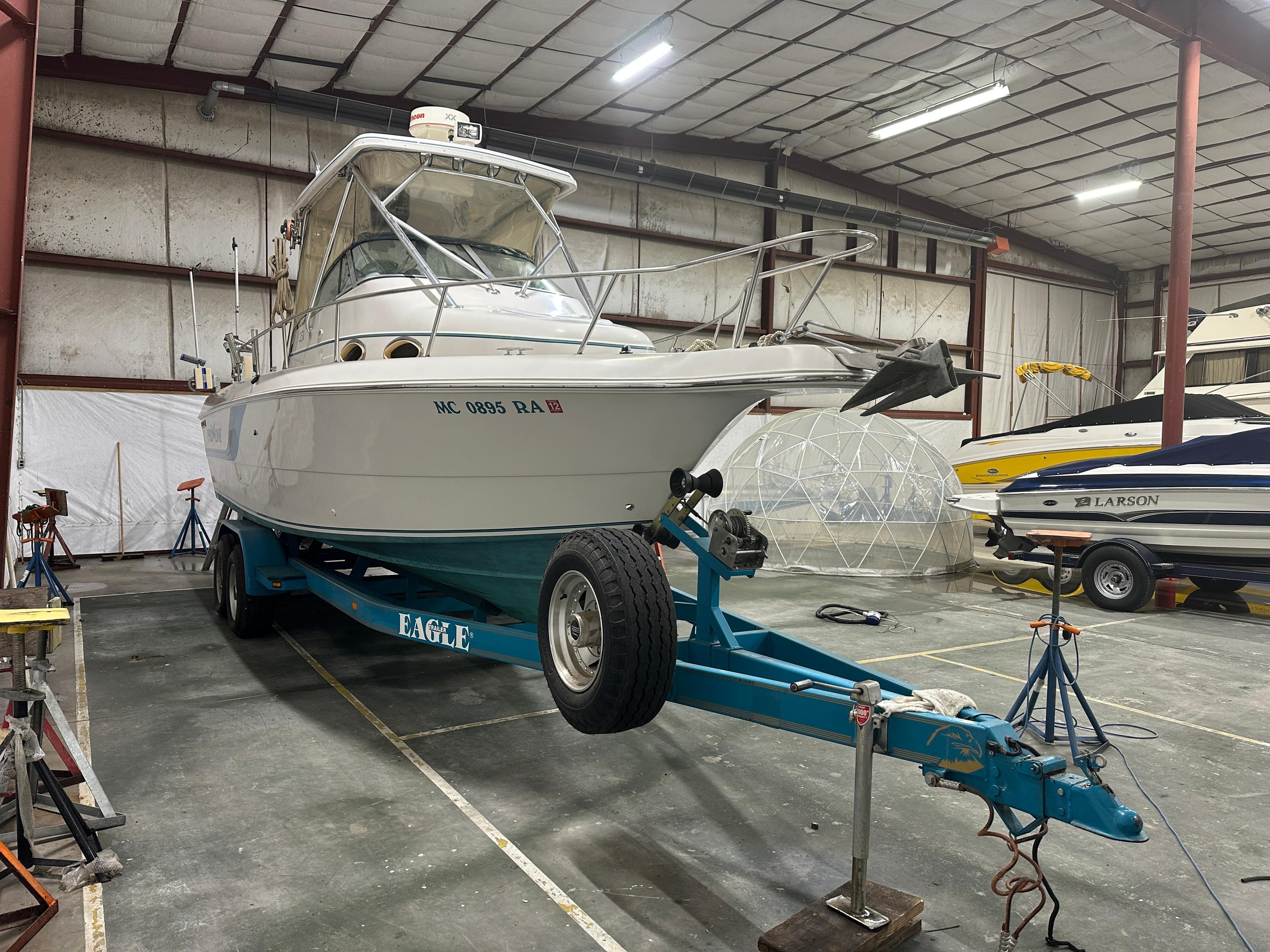 1996 Pro-Line 251 Walkaround I/O boat on trailer in indoor storage facility.