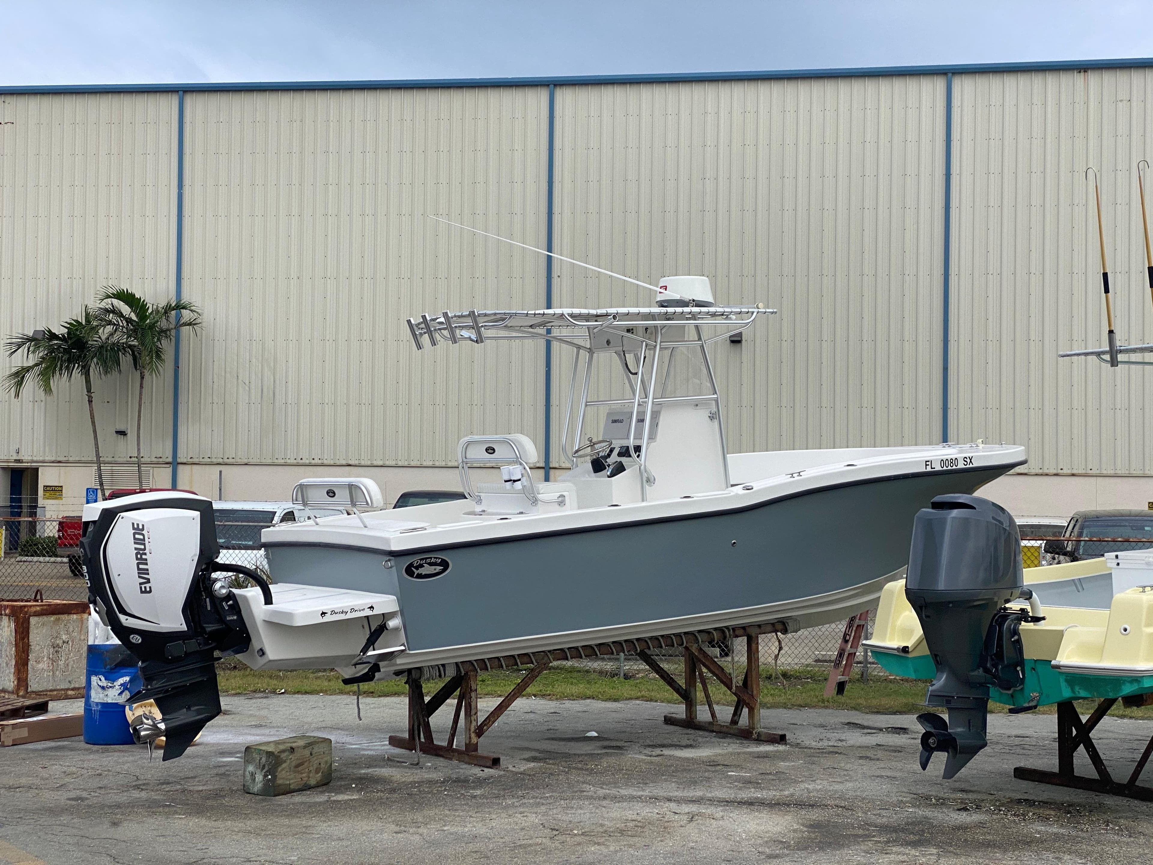 2021 Dusky 252 T boat with Evinrude engine, parked outdoors near a warehouse.