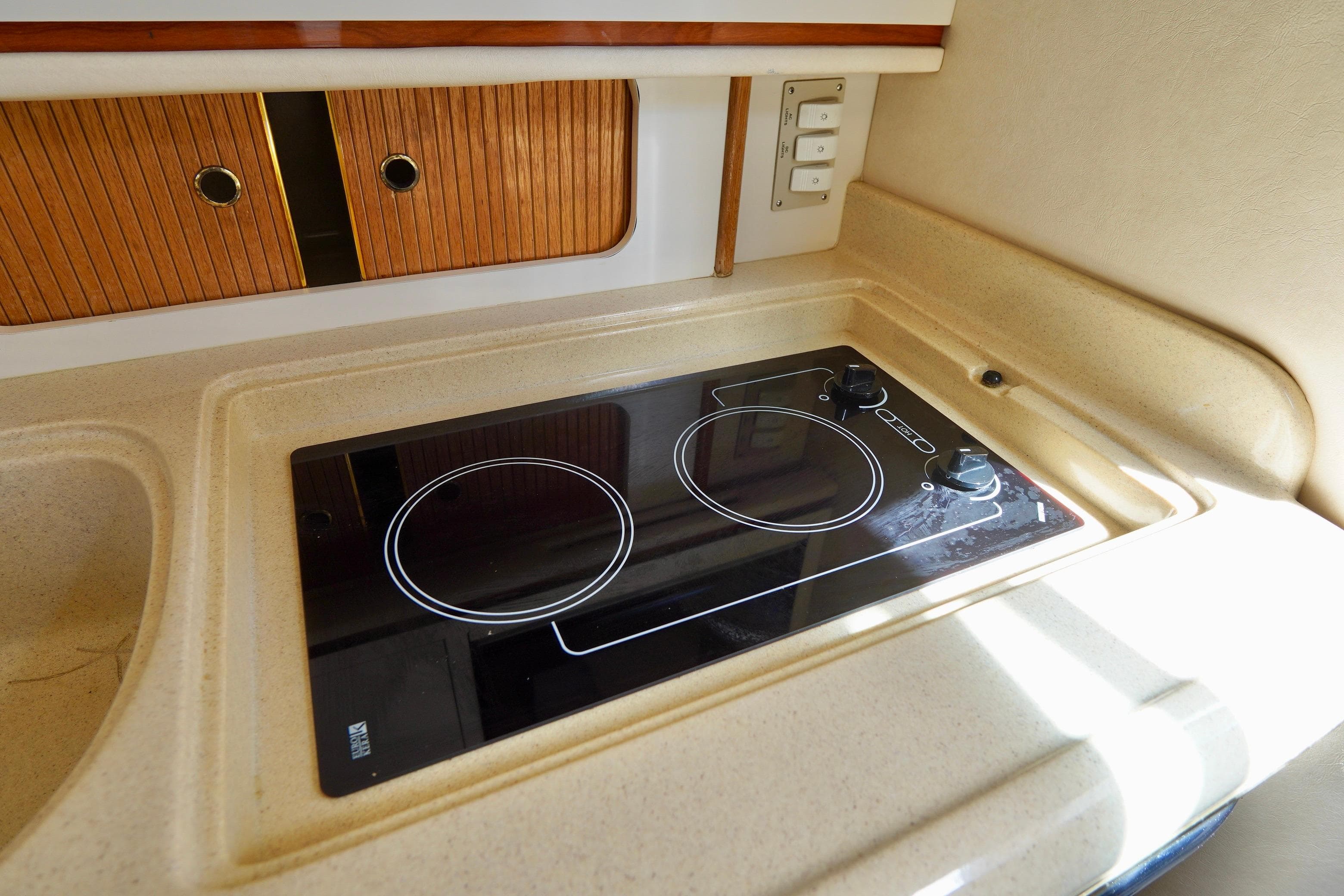 2000 Sea Ray 280 Sundancer kitchen with electric stove and wooden cabinets.