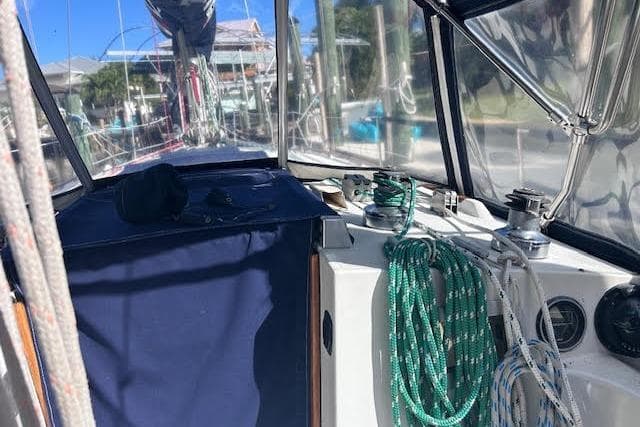 1987 Beneteau First 375 sailboat cockpit with ropes and winches, under clear skies.