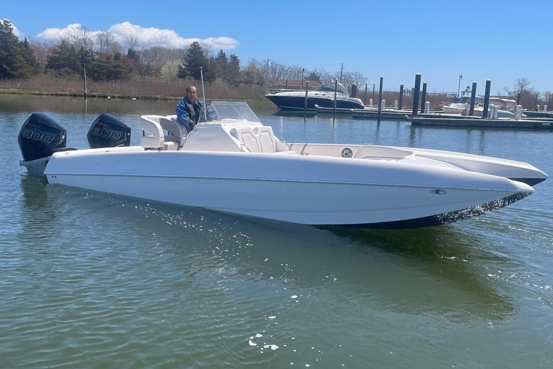 2025 Hustler 25 C3 Speedfish boat on calm water near a marina.
