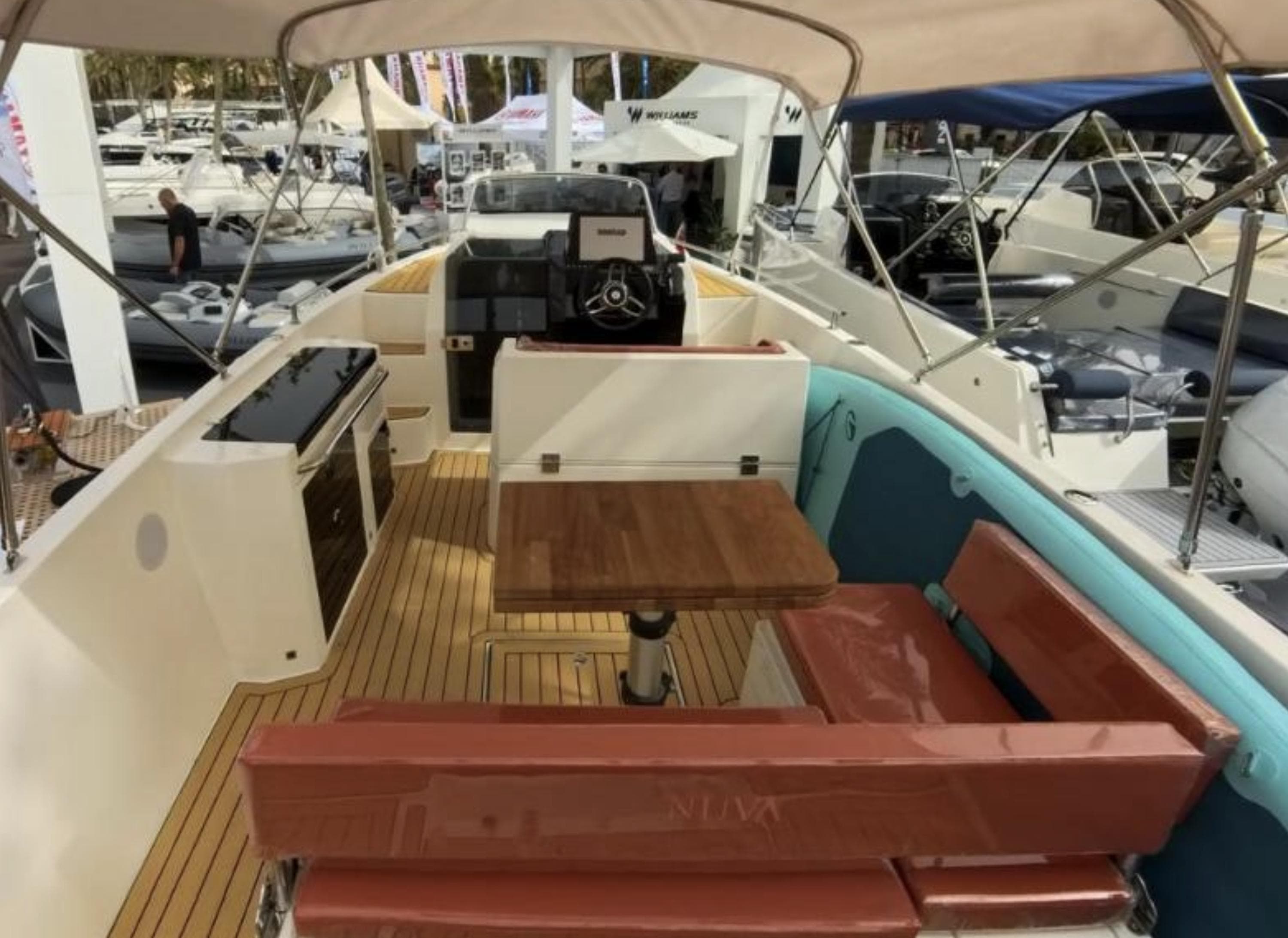 2025 Nuva M8 cabin boat interior with seating, table, and helm station.