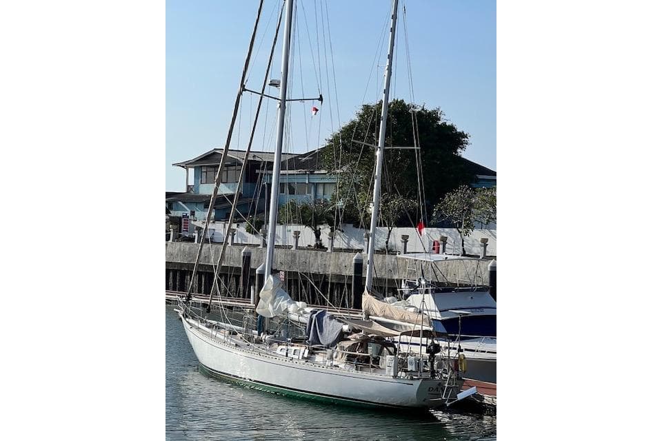 1985 Robert Clark Ketch sailboat docked at marina, clear sky background.