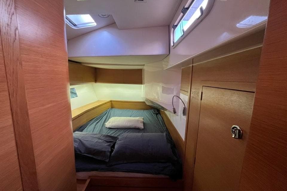 Cozy cabin interior of 2014 Salona Ker 63 yacht with wooden finish and bedding.