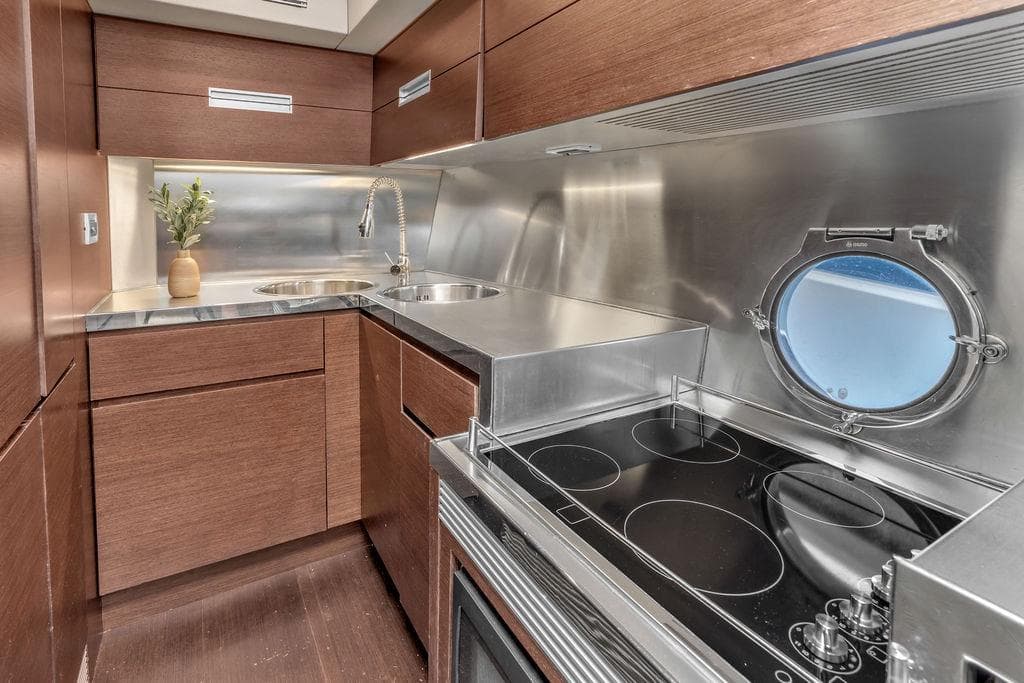 Modern kitchen in 2006 Azimut 68S yacht with stainless steel appliances and porthole window.