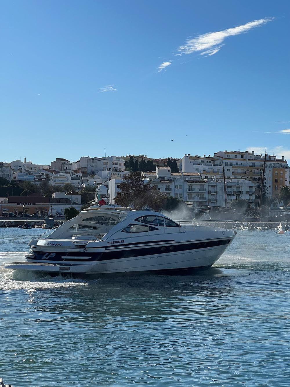 2001 Pershing 52 yacht cruising in a sunny coastal harbor.