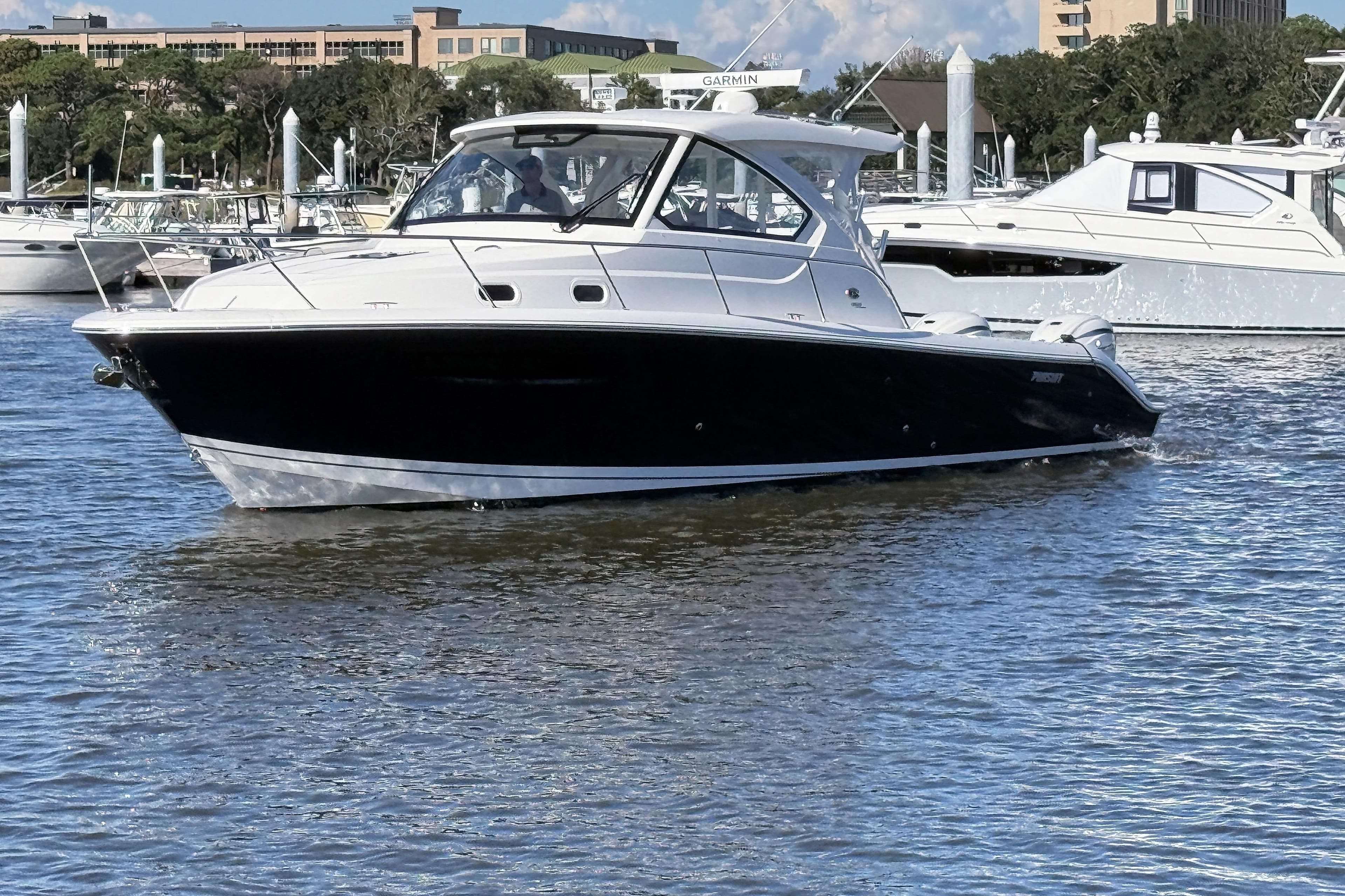 2026 Pursuit OS 355 Offshore boat cruising in a marina with other yachts.