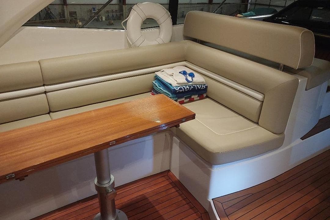 Luxurious interior of 2012 Sunseeker Portofino 48 yacht with beige seating and wooden table.