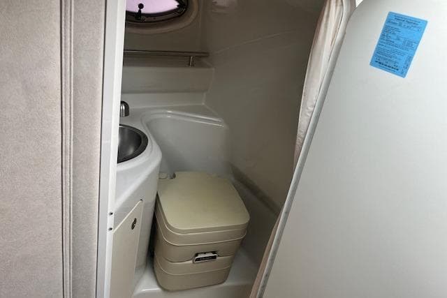 Compact bathroom in 2008 Sea Ray 240 Sundancer boat with sink and portable toilet.