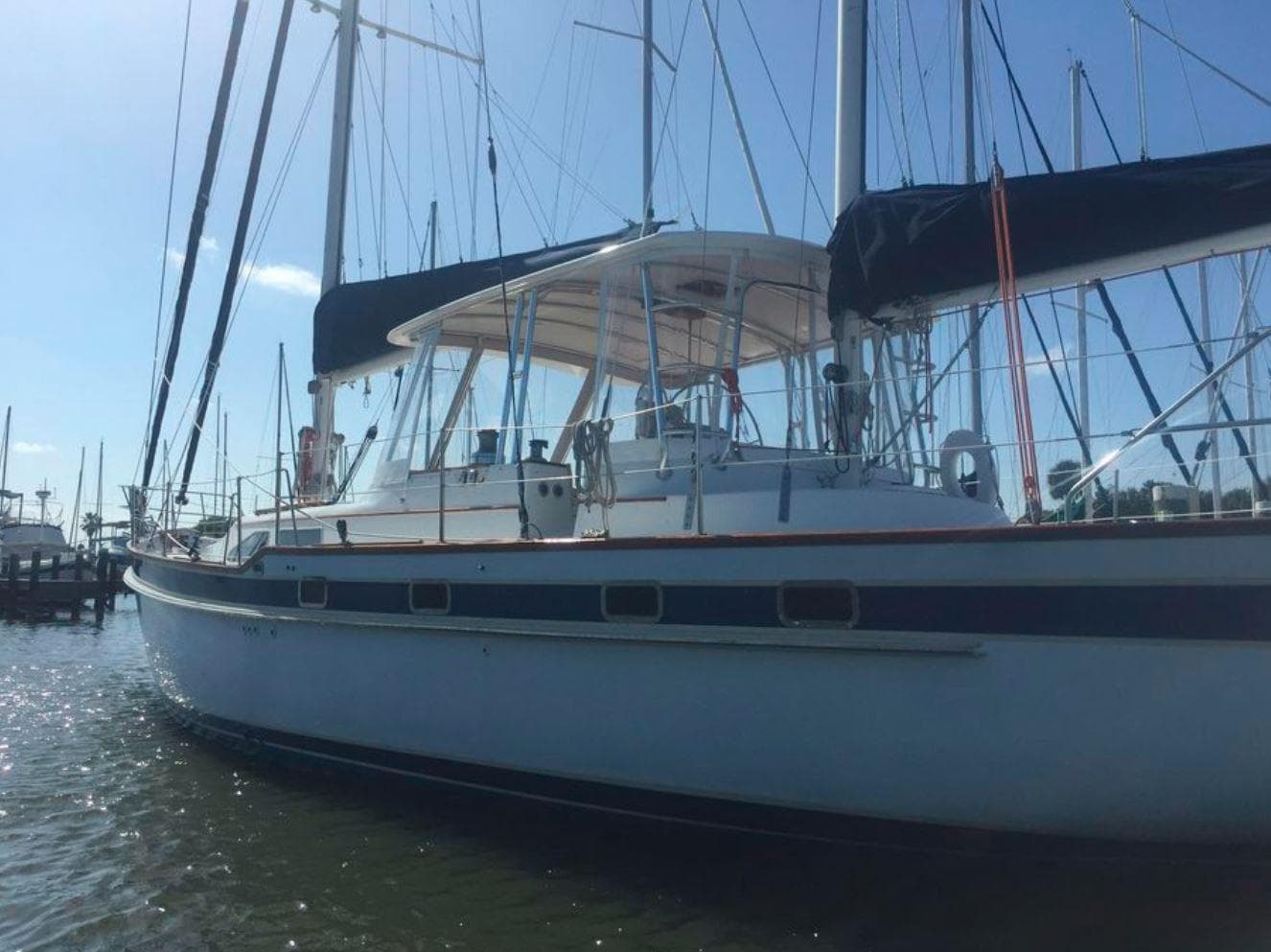 Irwin 54 sailboat, 1990 model, docked in marina under clear sky.