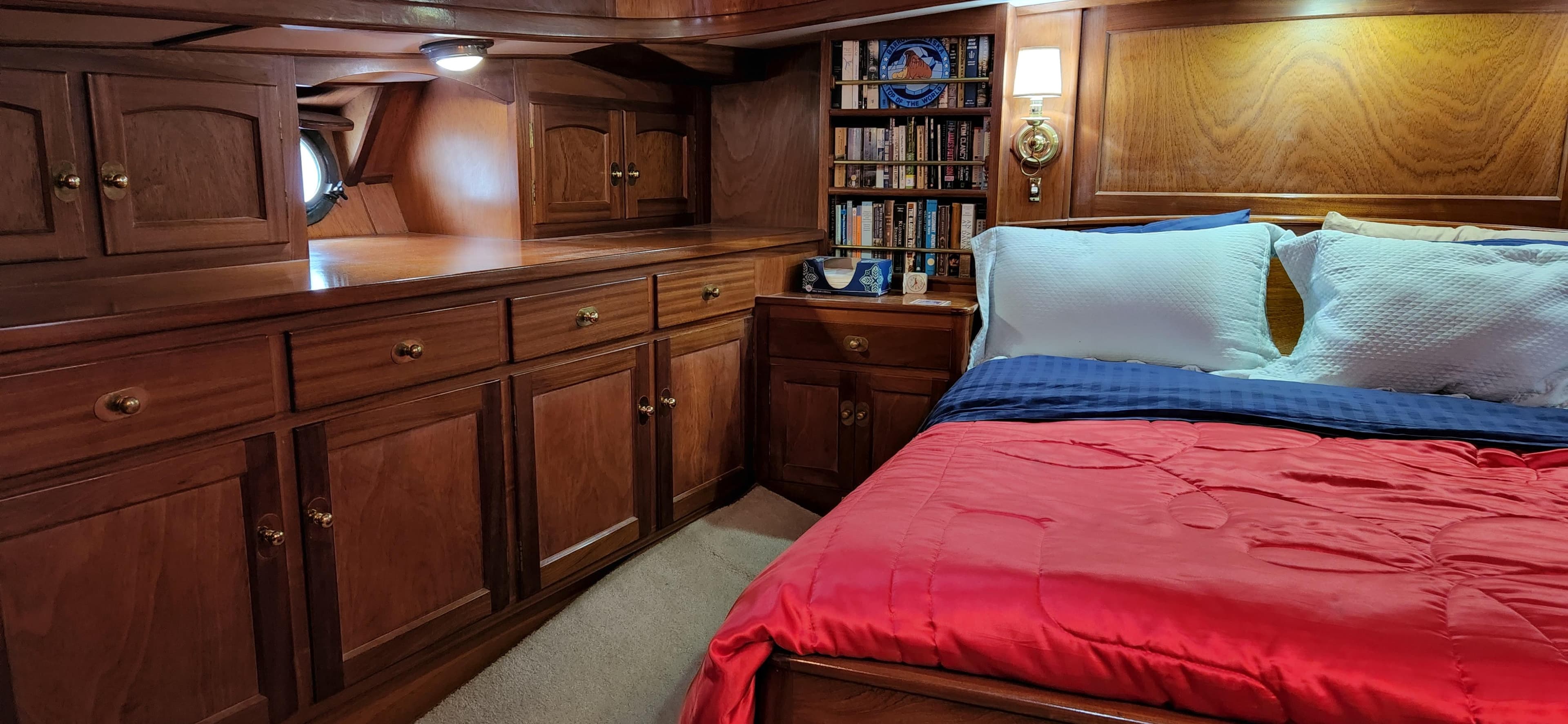 Luxurious 1983 Thackwray Custom Pilothouse Motorsailer cabin with wood paneling and cozy bedding.