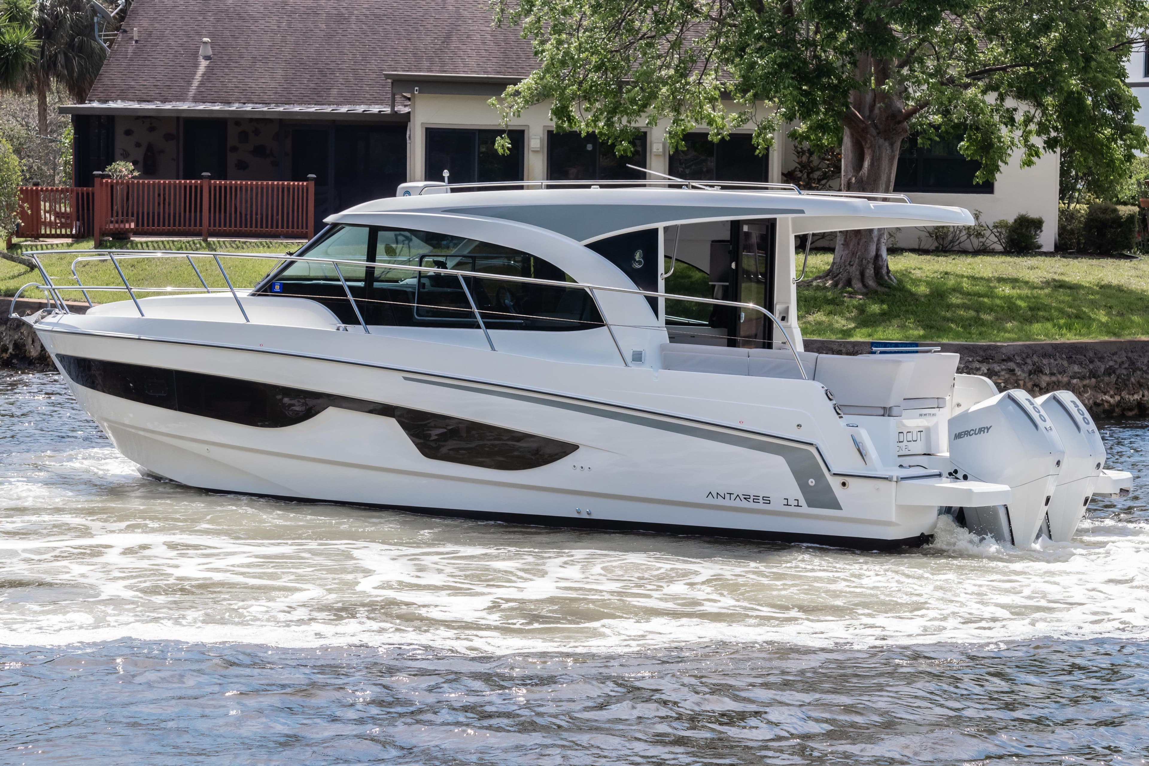 2023 Beneteau Antares 11 cruising on a river near a house.