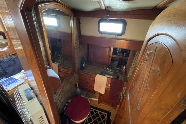 Interior of 1982 Formosa 42 sailboat bathroom with wooden cabinetry and mirror.