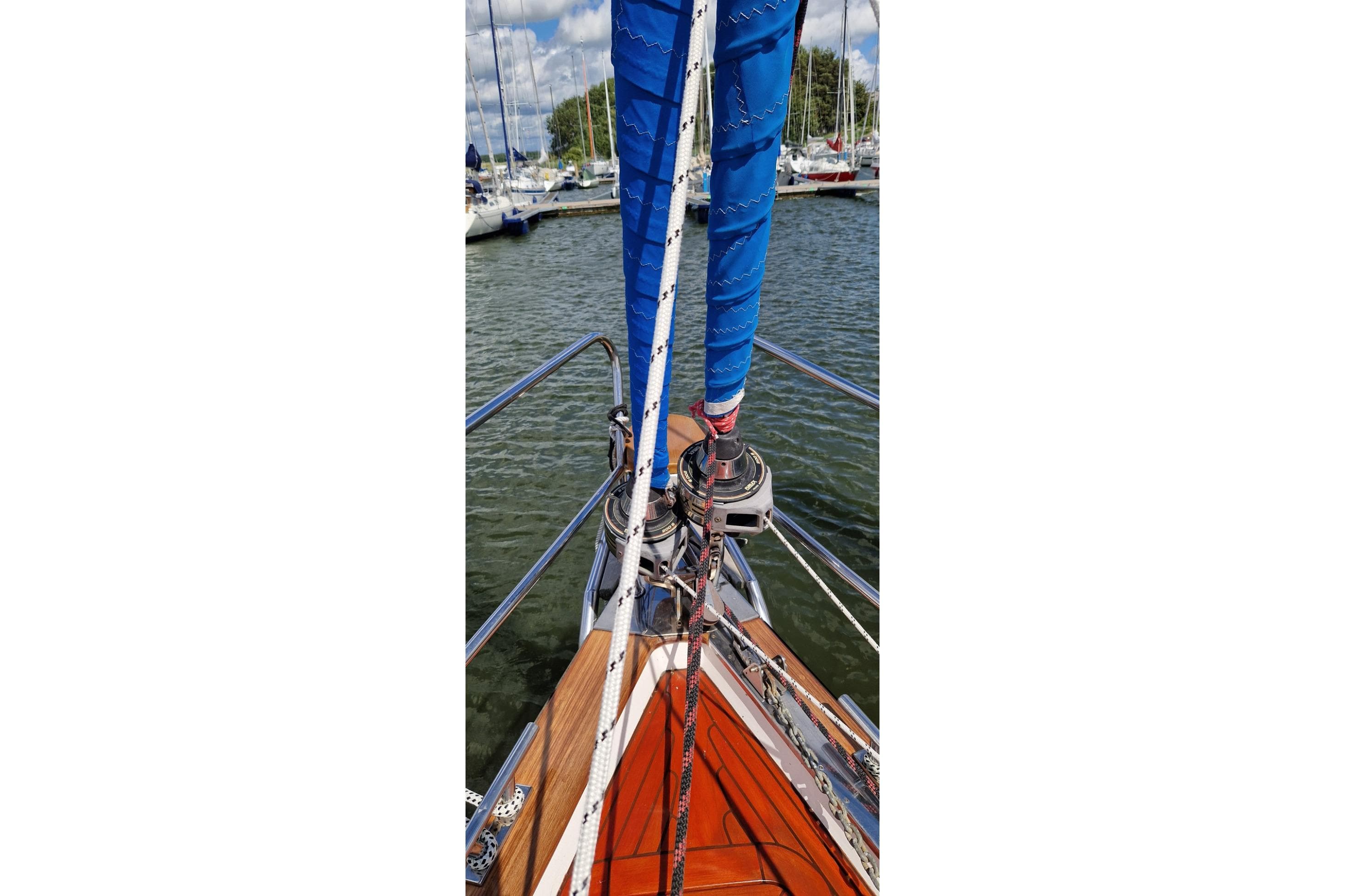 Bow of 2002 Vilm 116 sailboat with blue sail and marina view.
