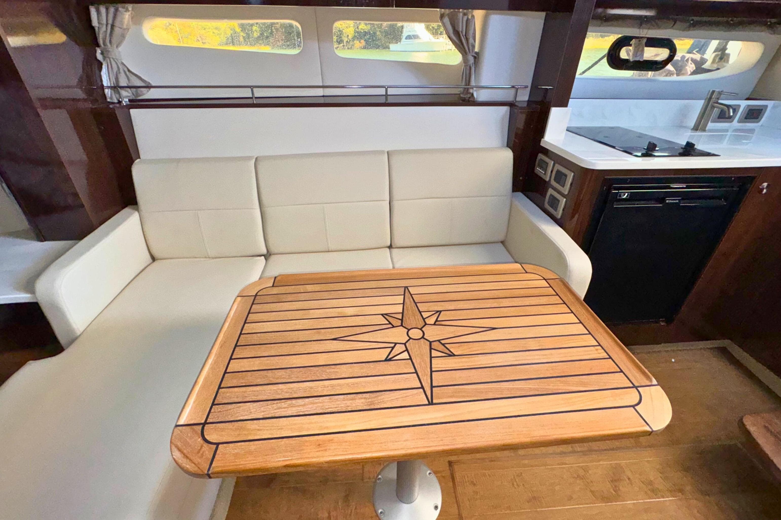 Interior of 2017 Sea Ray Sundancer 350 Coupe with elegant seating and wooden table.