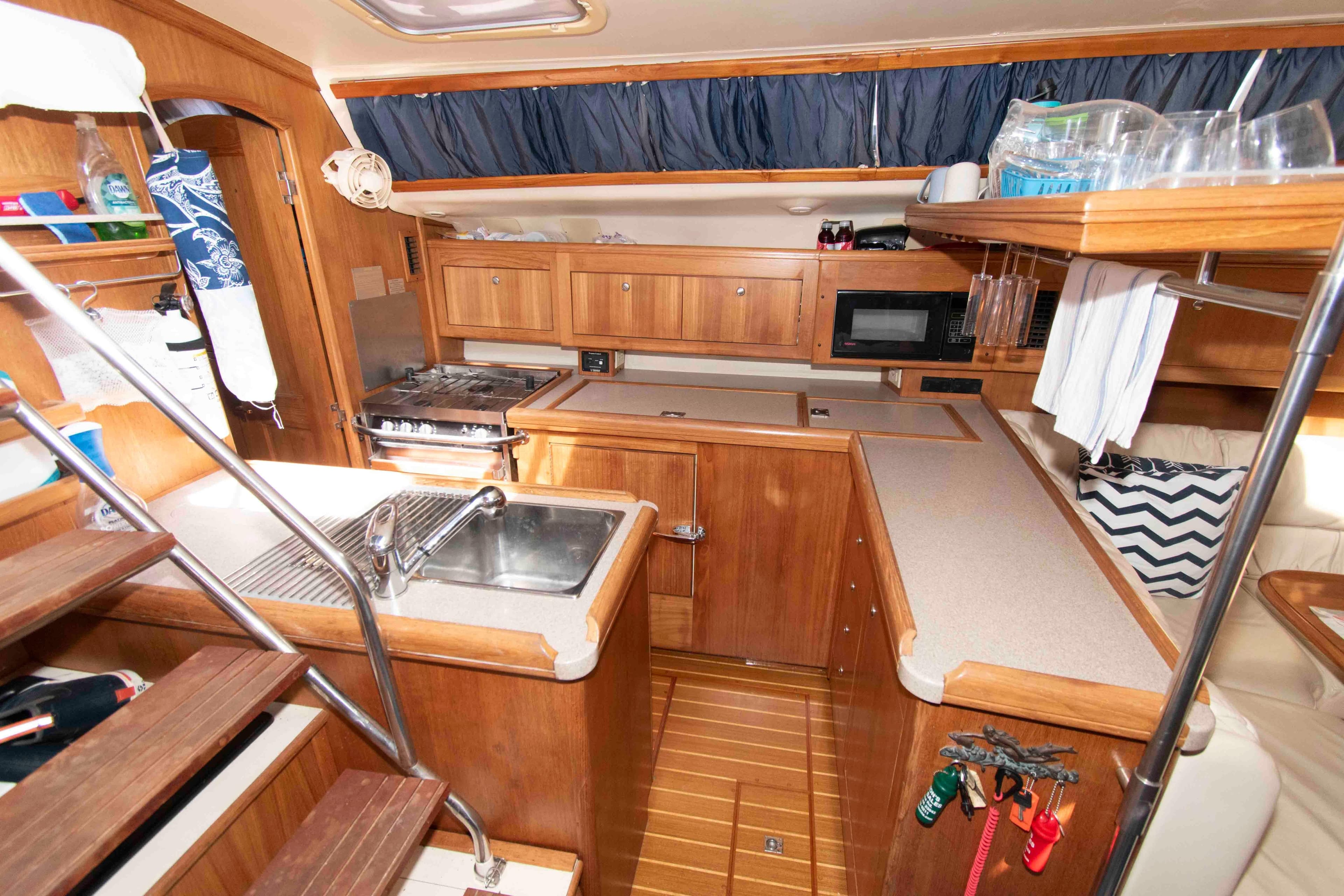 Interior of 2001 Hunter 460 yacht kitchen with wooden cabinetry and modern appliances.
