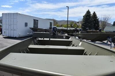 2025 Lowe L1648M Jon boat displayed outdoors with trees and container in background.