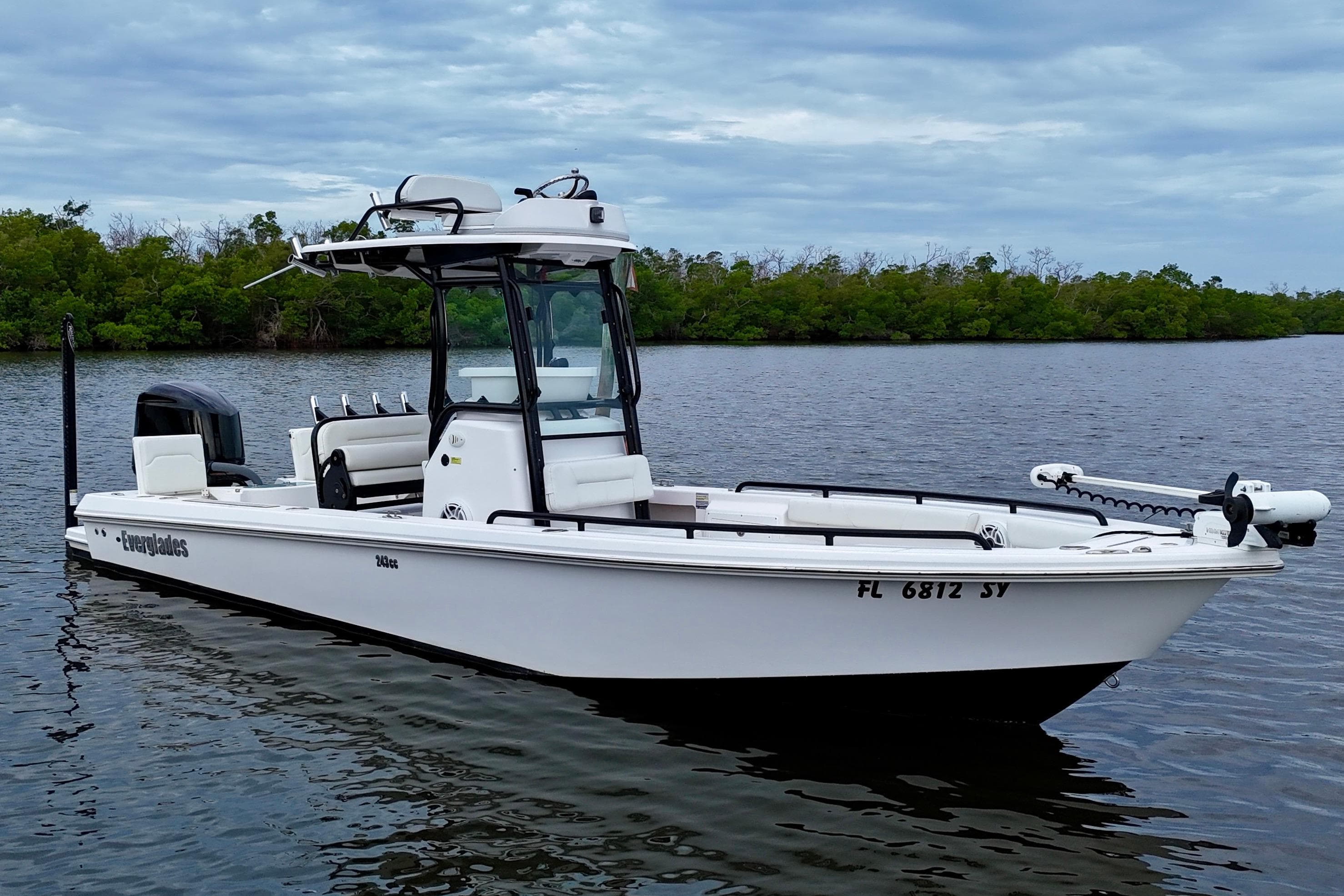 2021 Everglades 243 Center Console boat on calm water, with lush greenery in the background.