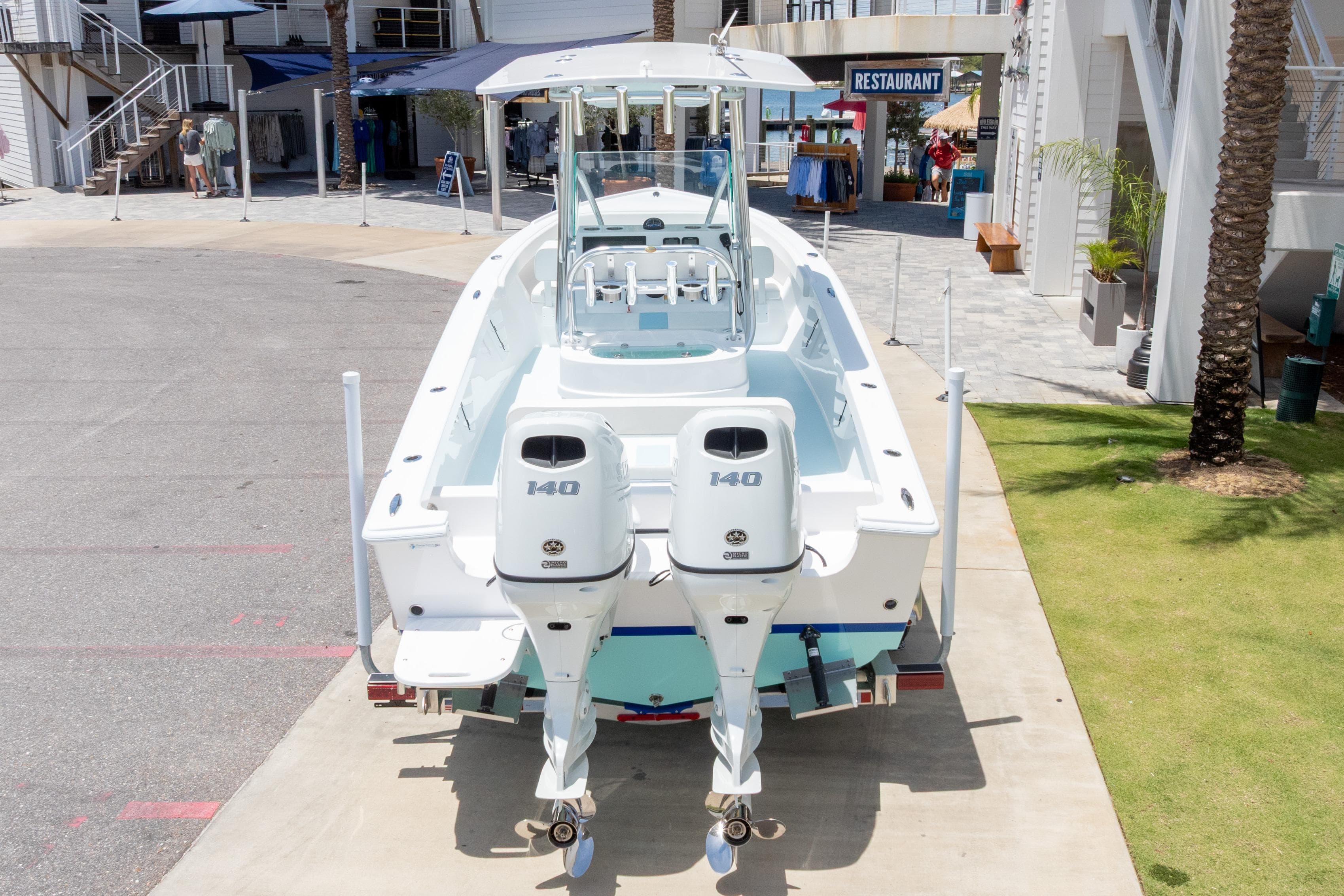 2026 Albury Brothers 23 Forward Seating boat with twin 140 engines, docked near a restaurant.