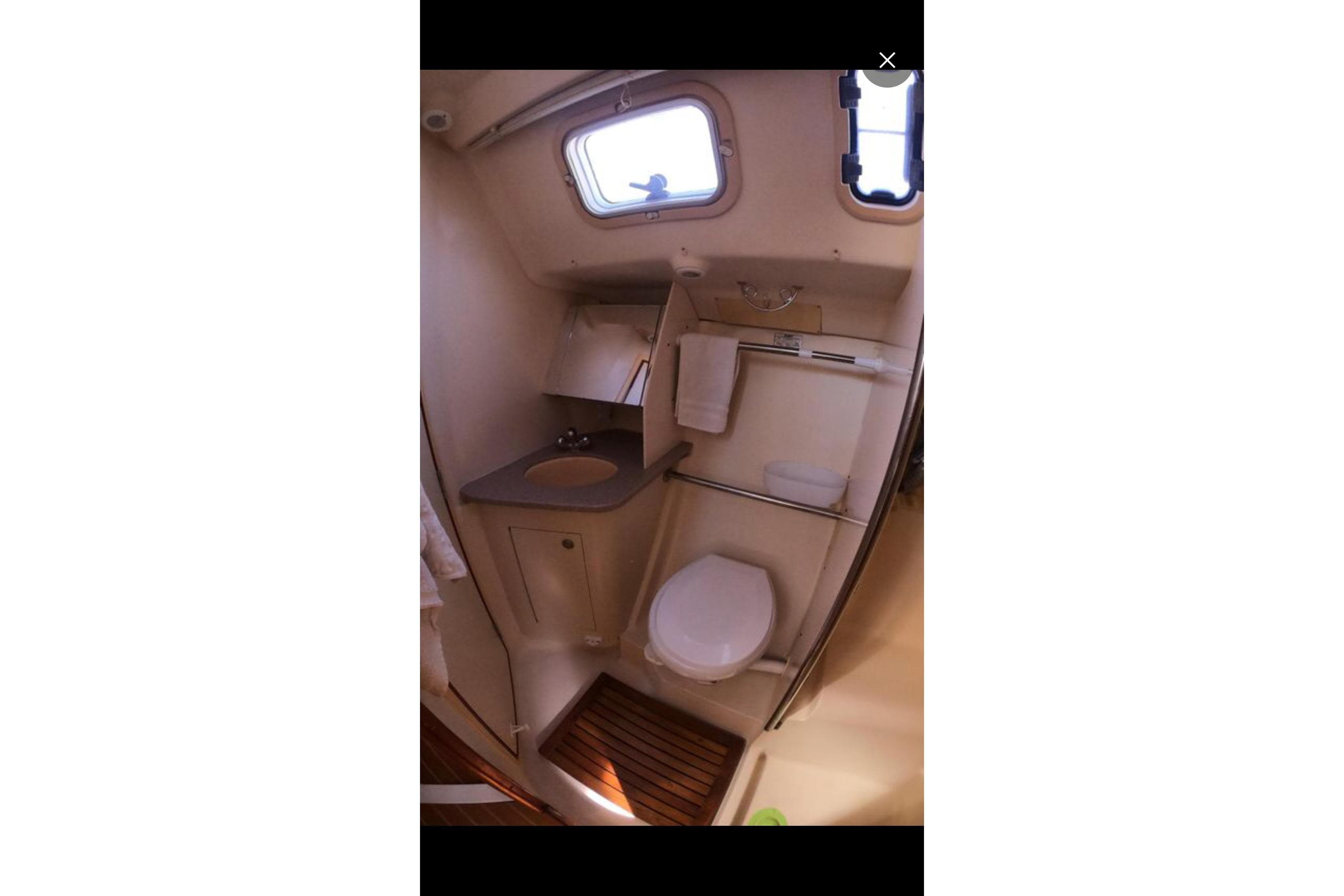 Compact bathroom in a 2002 Hunter 410 yacht, featuring a sink, toilet, and window.