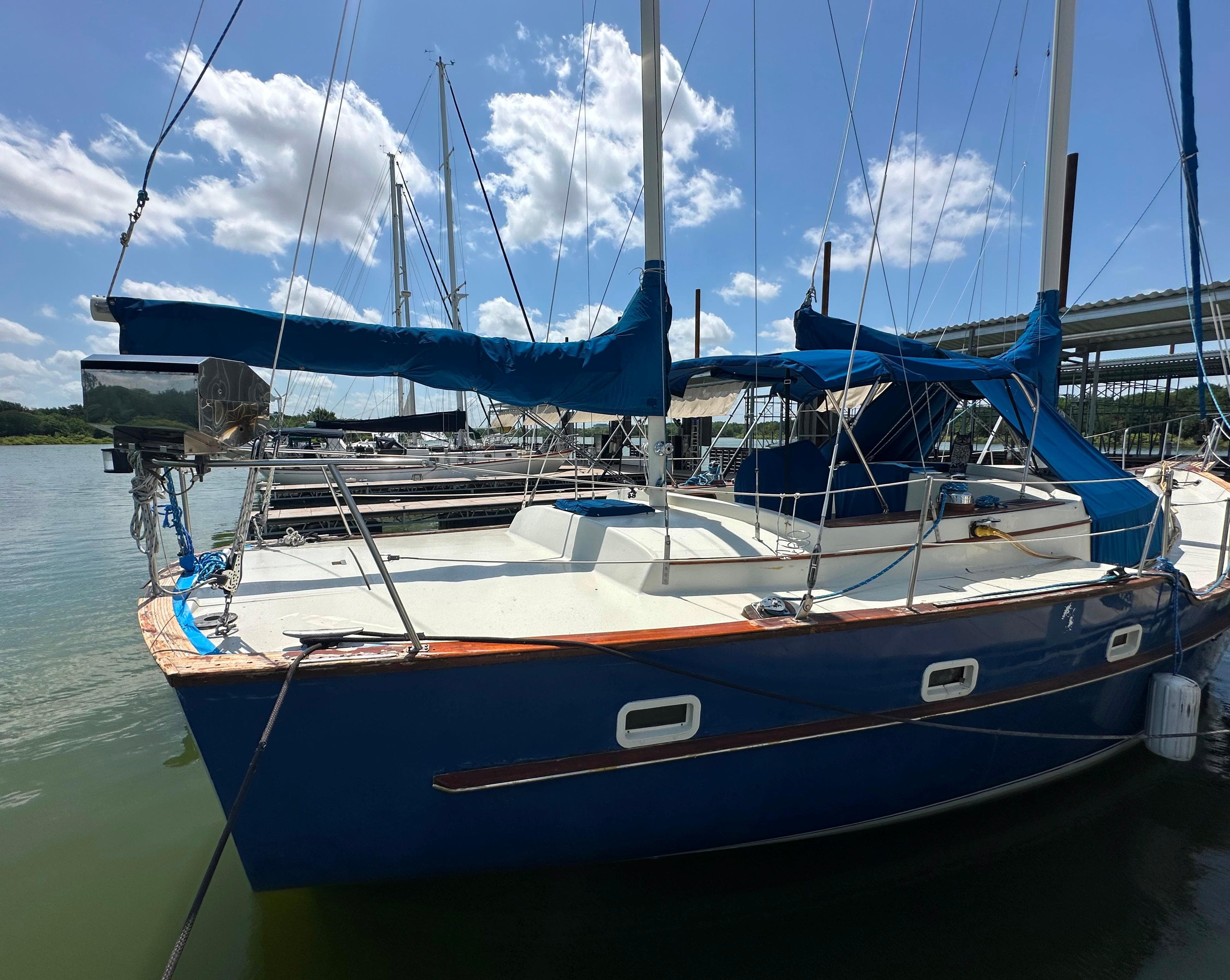 1982 Irwin 46 sailboat docked, featuring blue hull and covered sails under a sunny sky.