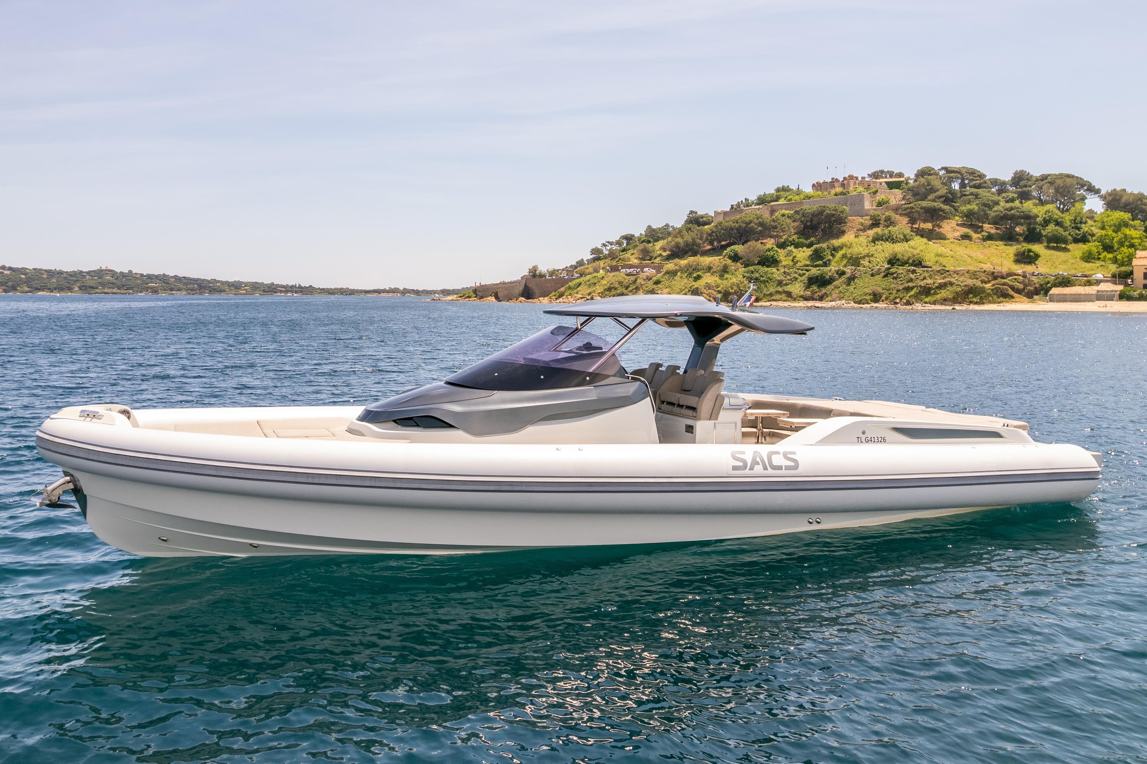 2022 SACS Strider 15 luxury boat on calm blue water near a scenic coastline.