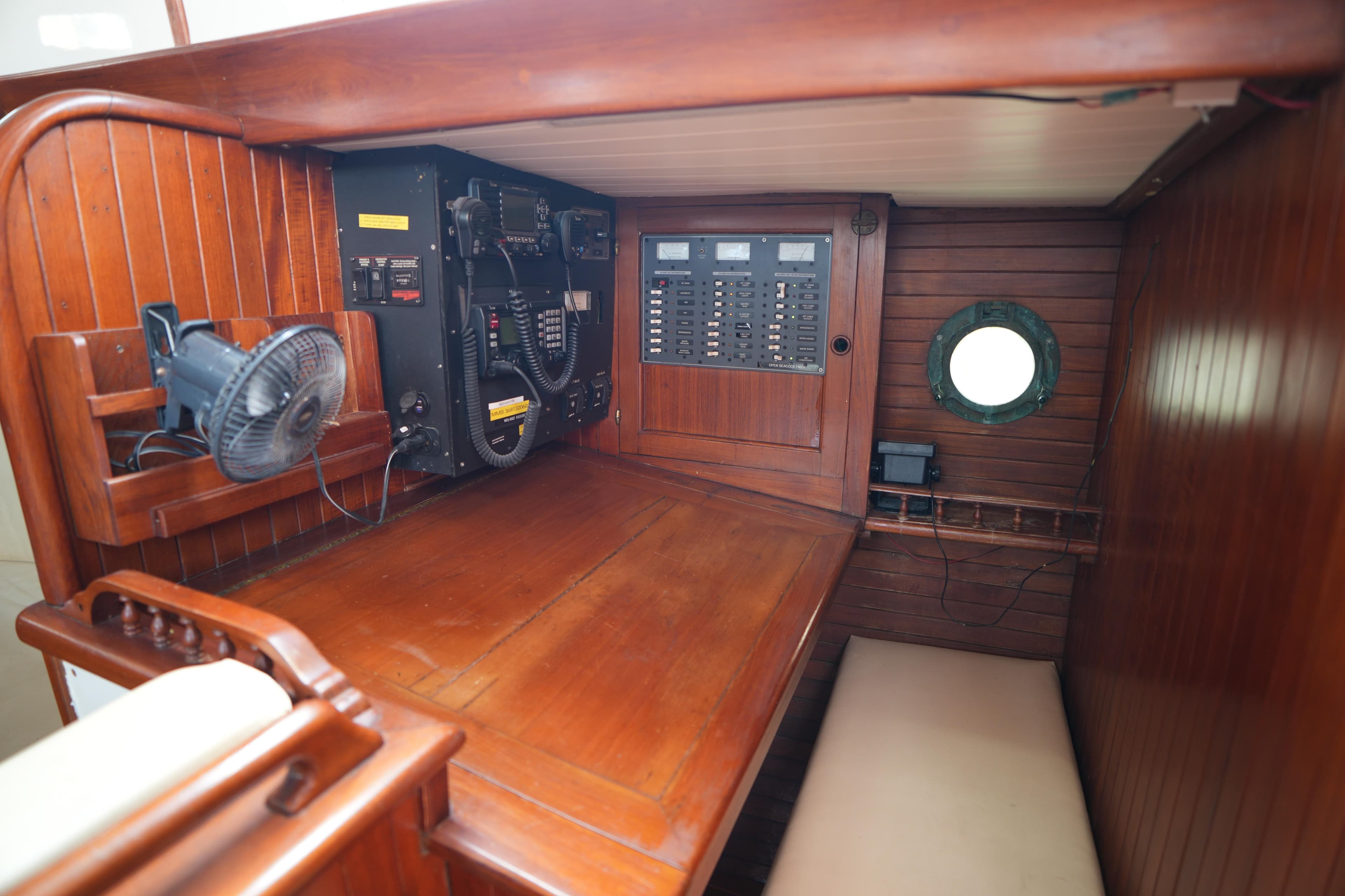 Wooden interior of 1982 Vagabond 47 sailboat with navigation equipment and porthole.