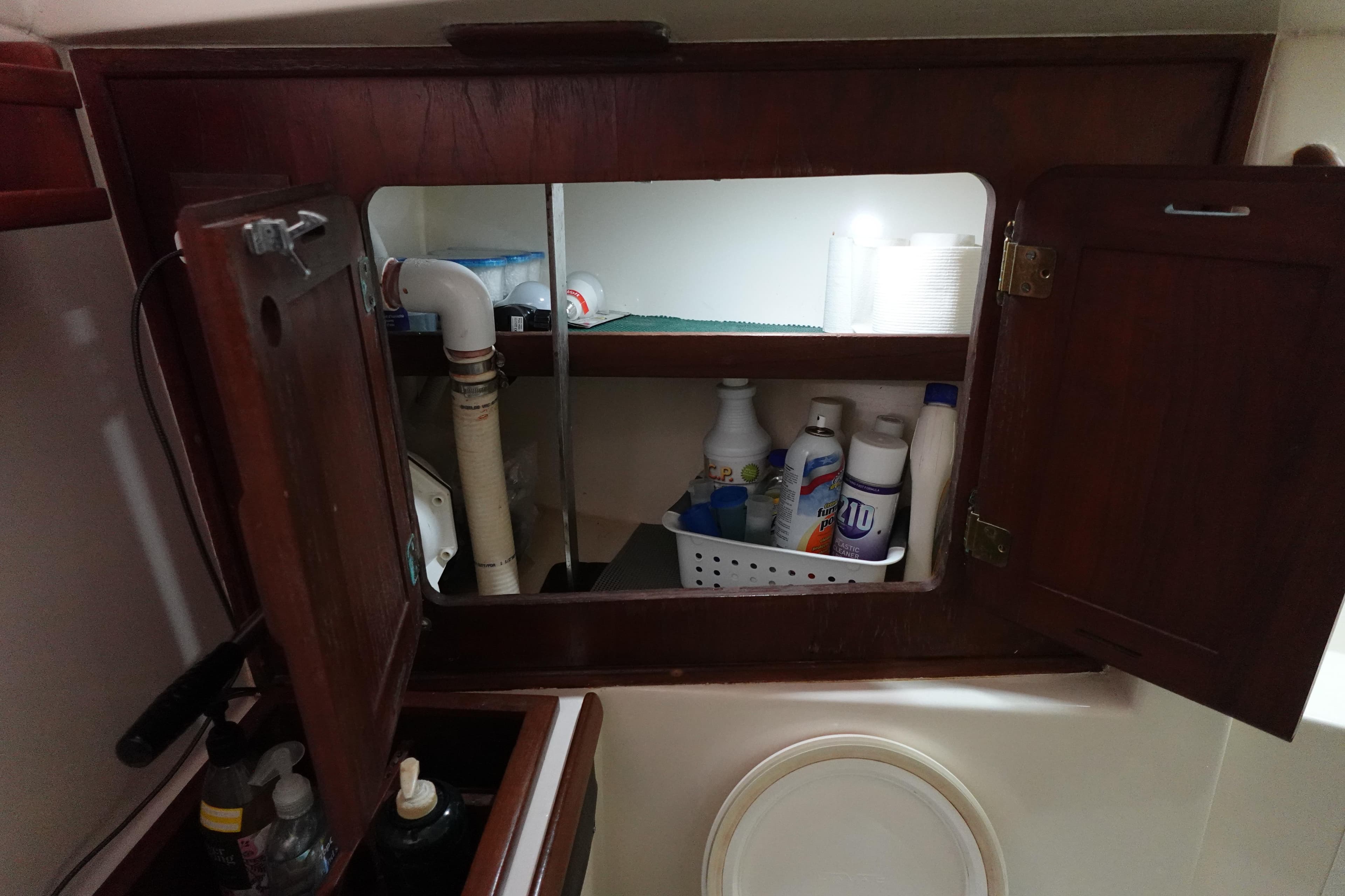 1978 Morgan 382 sailboat bathroom cabinet with cleaning supplies and plumbing.