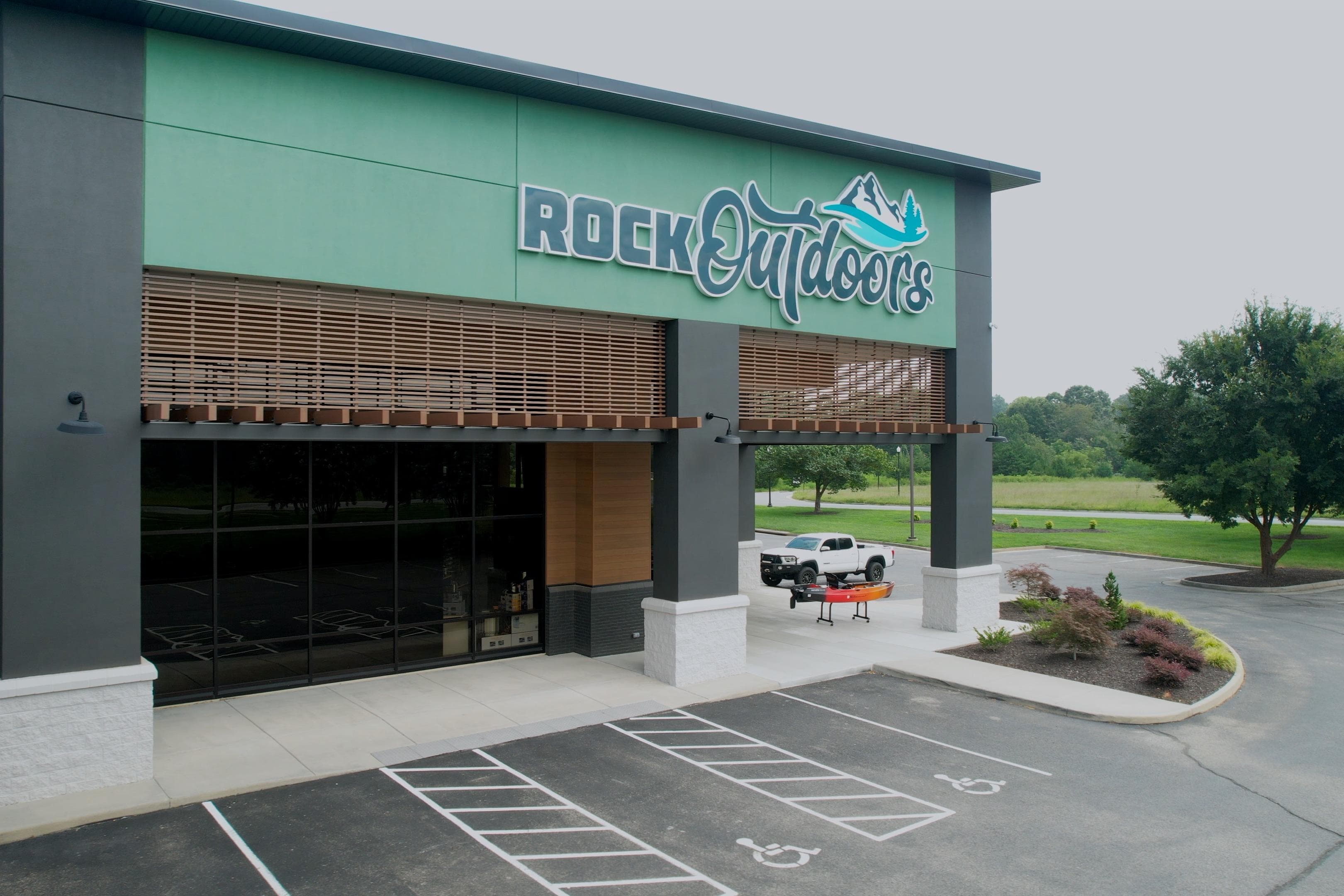 Outdoor store with "Rock Outdoors" sign, parking lot, and greenery. Bass Cat Pantera Classic 2026.