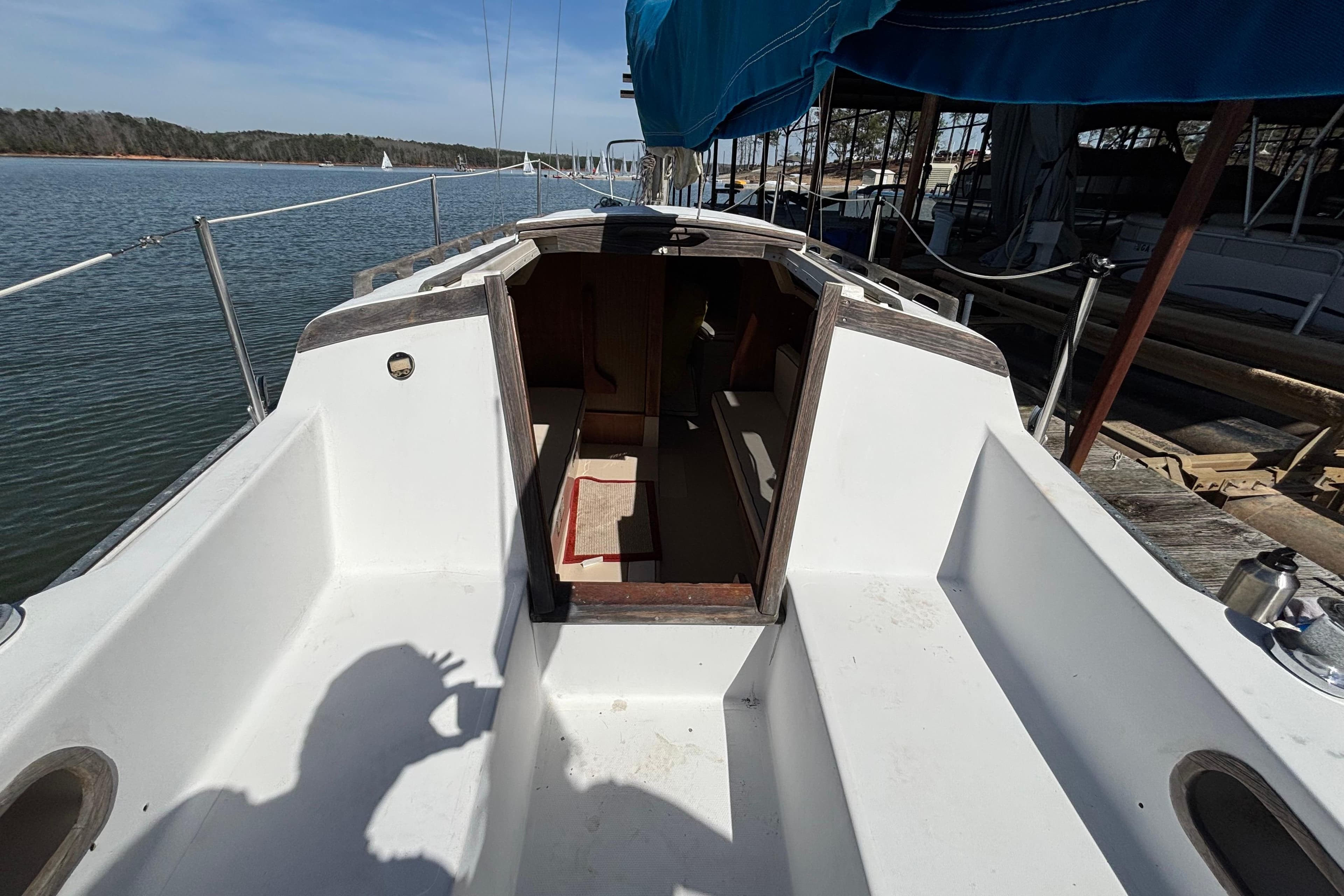 1983 Catalina 25 sailboat cockpit with open cabin, docked by calm waters.