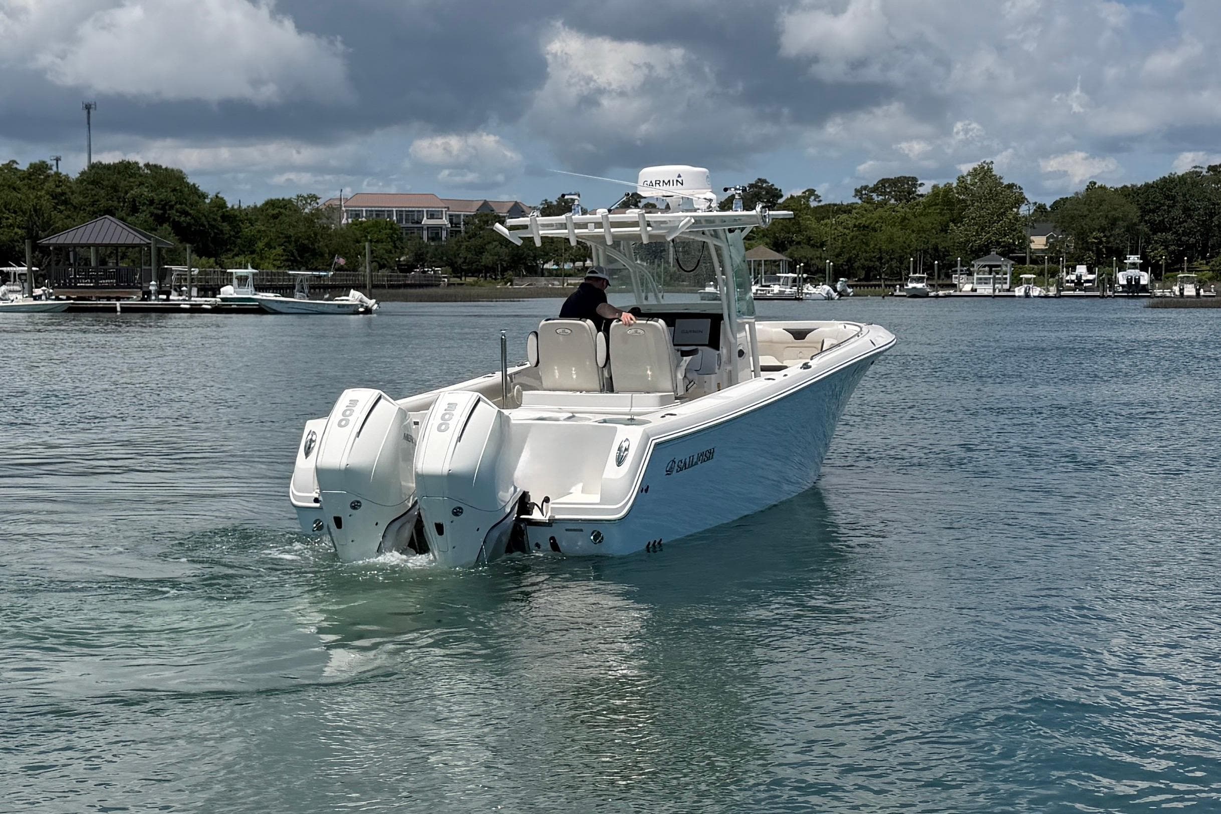 2021 Sailfish 290 CC boat cruising on a calm lake under a cloudy sky.