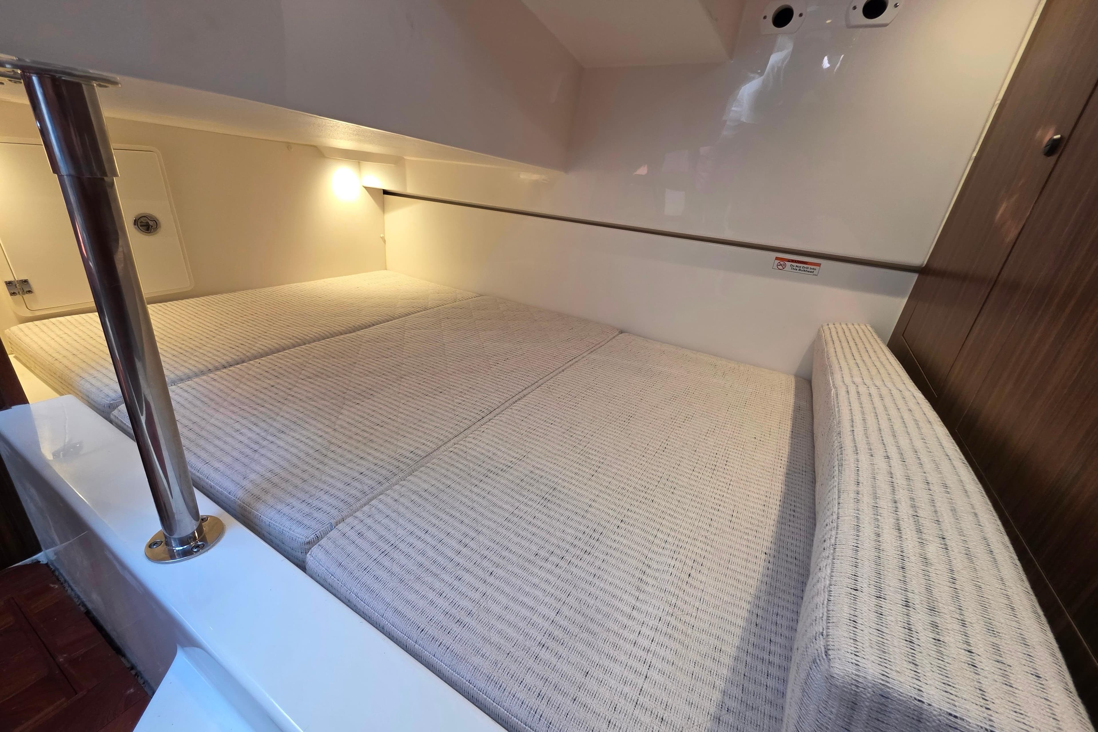 2024 Pursuit OS 325 Offshore cabin interior with cozy bedding and ambient lighting.