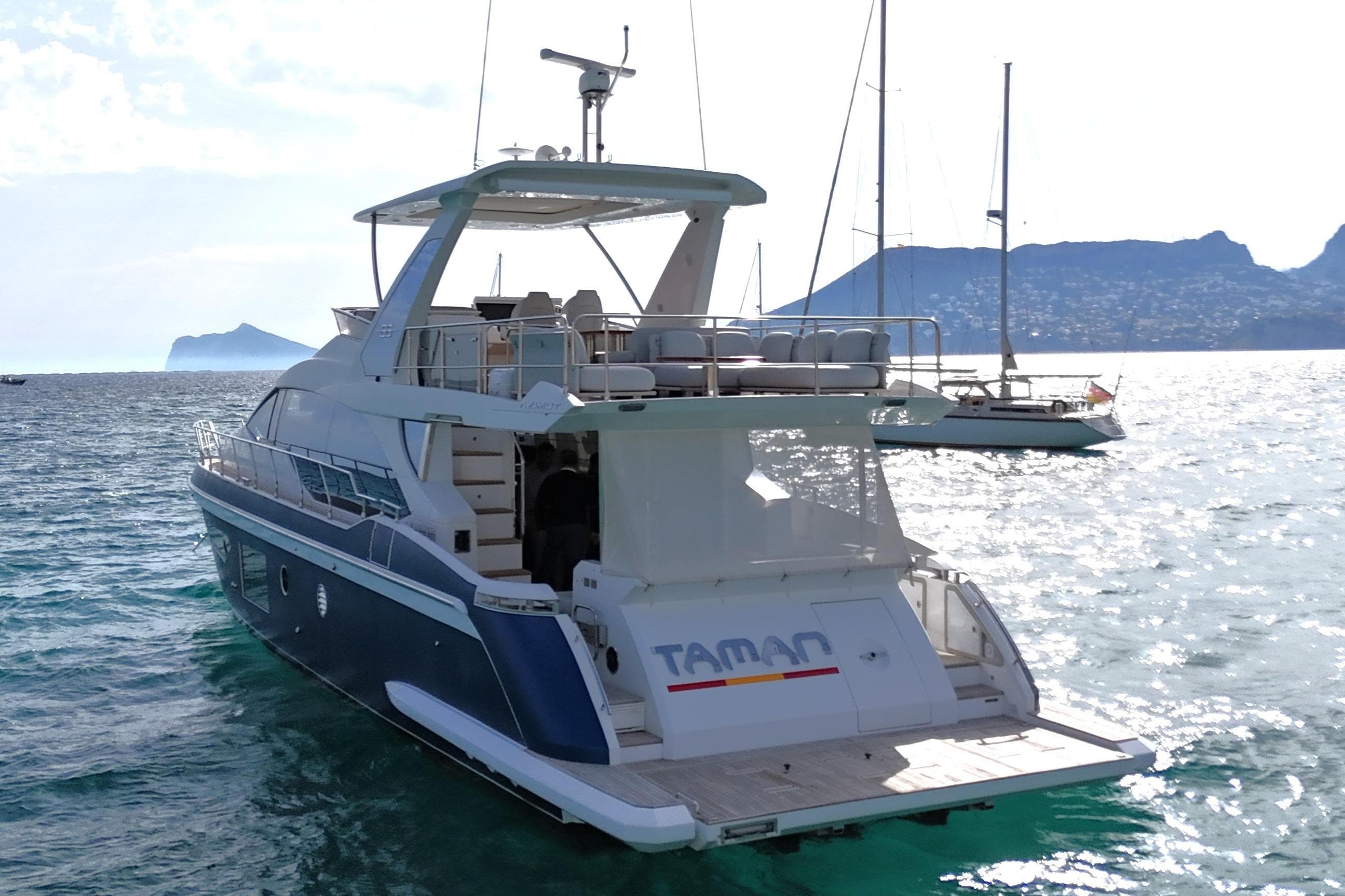 Luxury Azimut 66 yacht from 2021 on serene waters with scenic mountain backdrop.