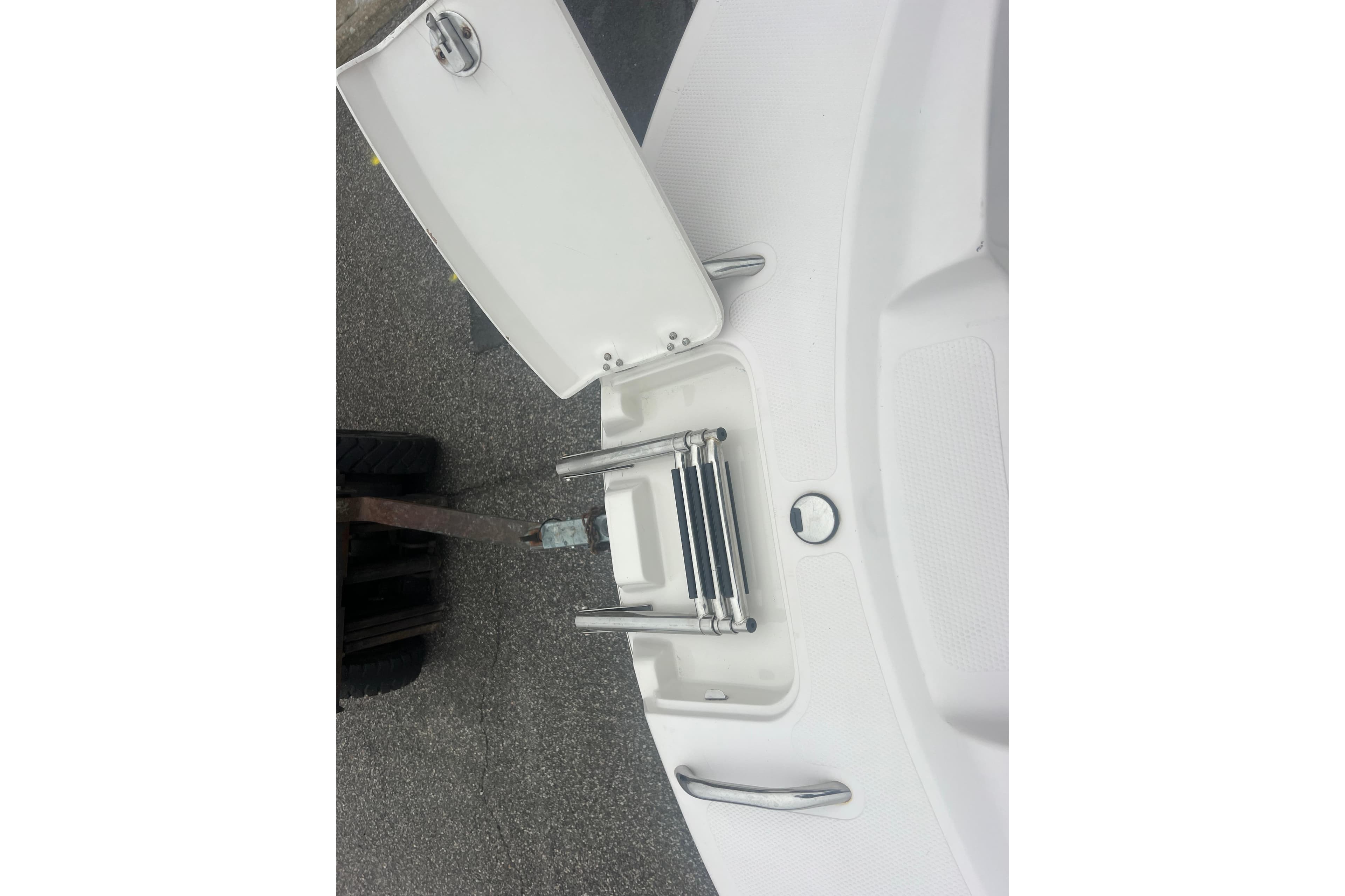 2005 Tahoe 234 boat with folded swim ladder on deck.