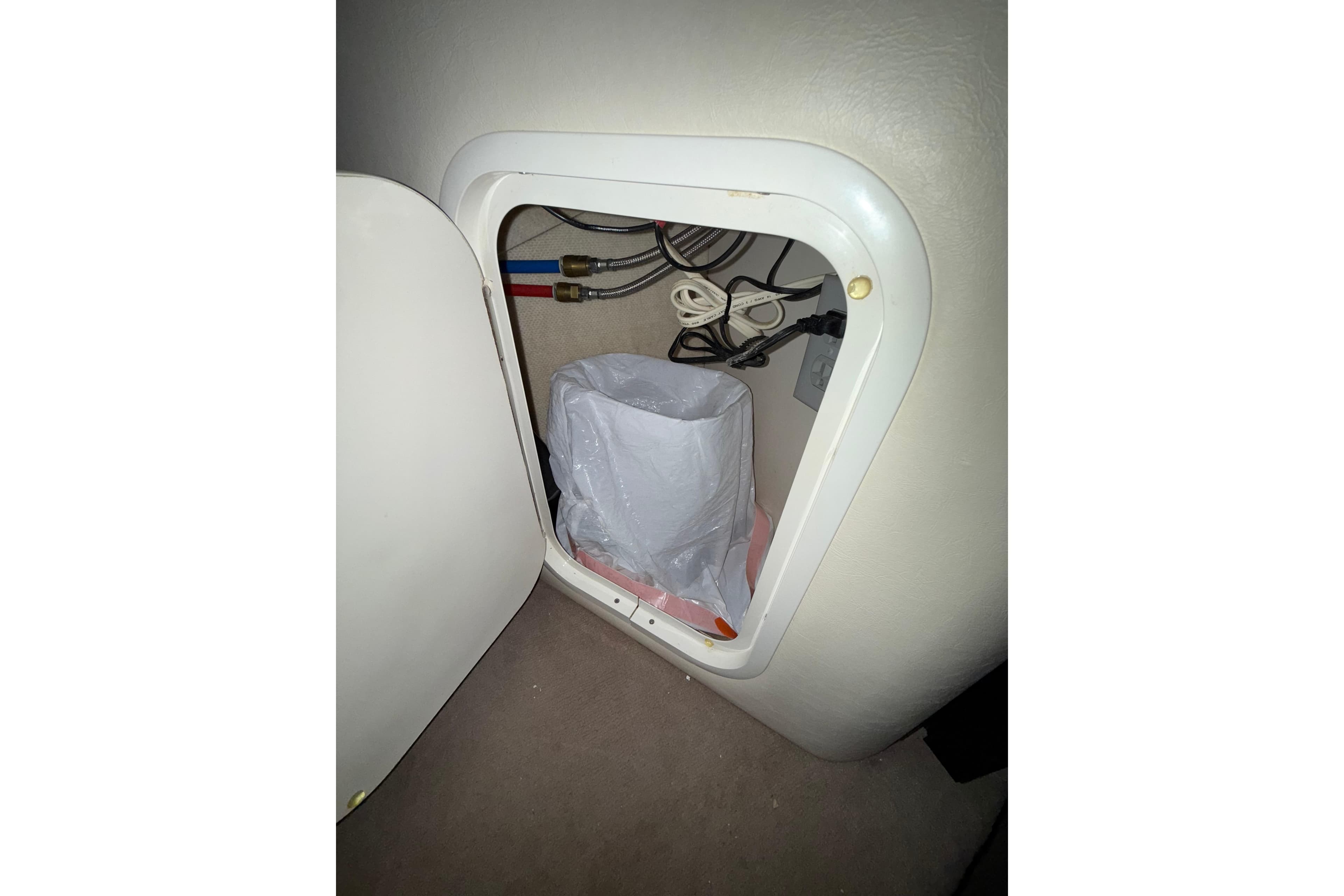 Storage compartment inside a 2000 Sea Ray 240 Sundancer boat, showing wiring and a plastic bag.